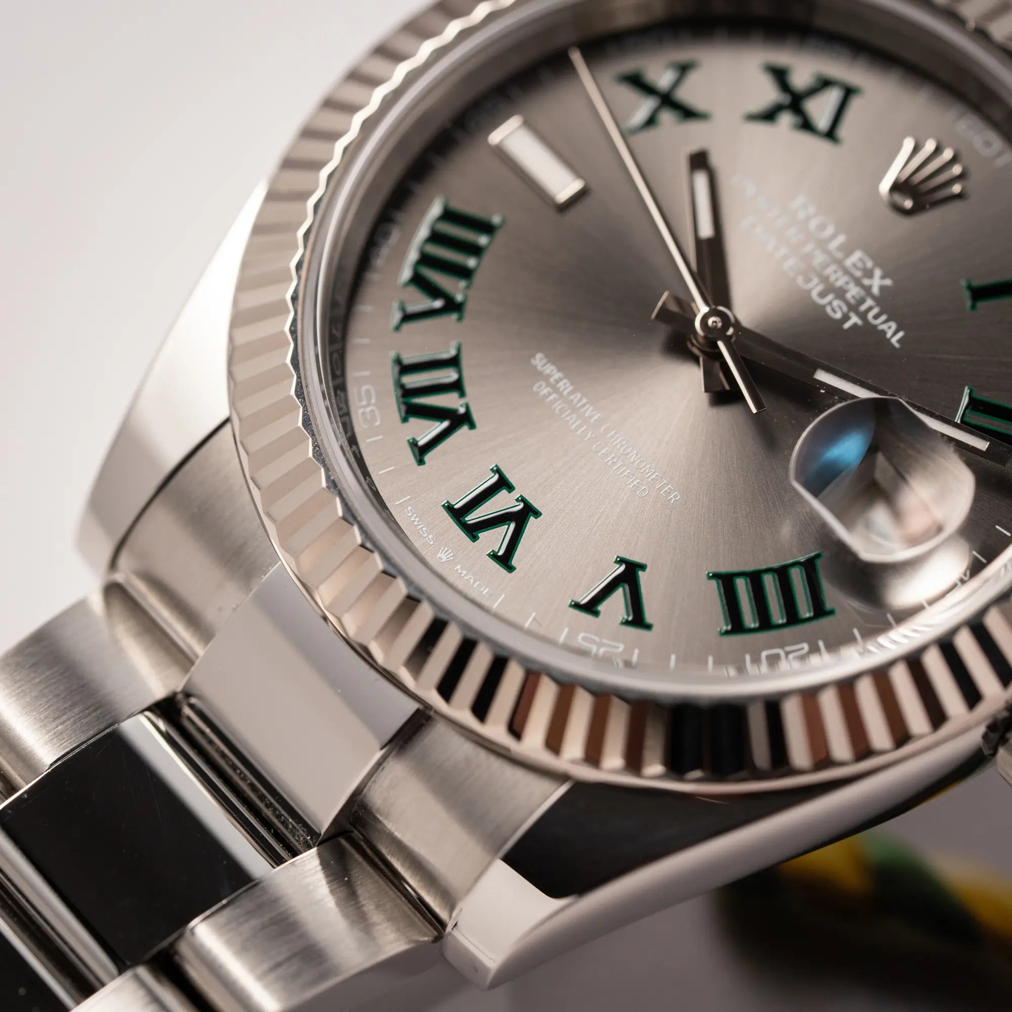 Detailaufnahme zeigt den rechten unteren Bandanstoß der Rolex Datejust 41 der Referenz 126334 mit geriffelter Weißgold-Lünette und Oyster-Stahlband mit dem grauen Wimbledon-Zifferblatt mit schwarz-grünen Indizes