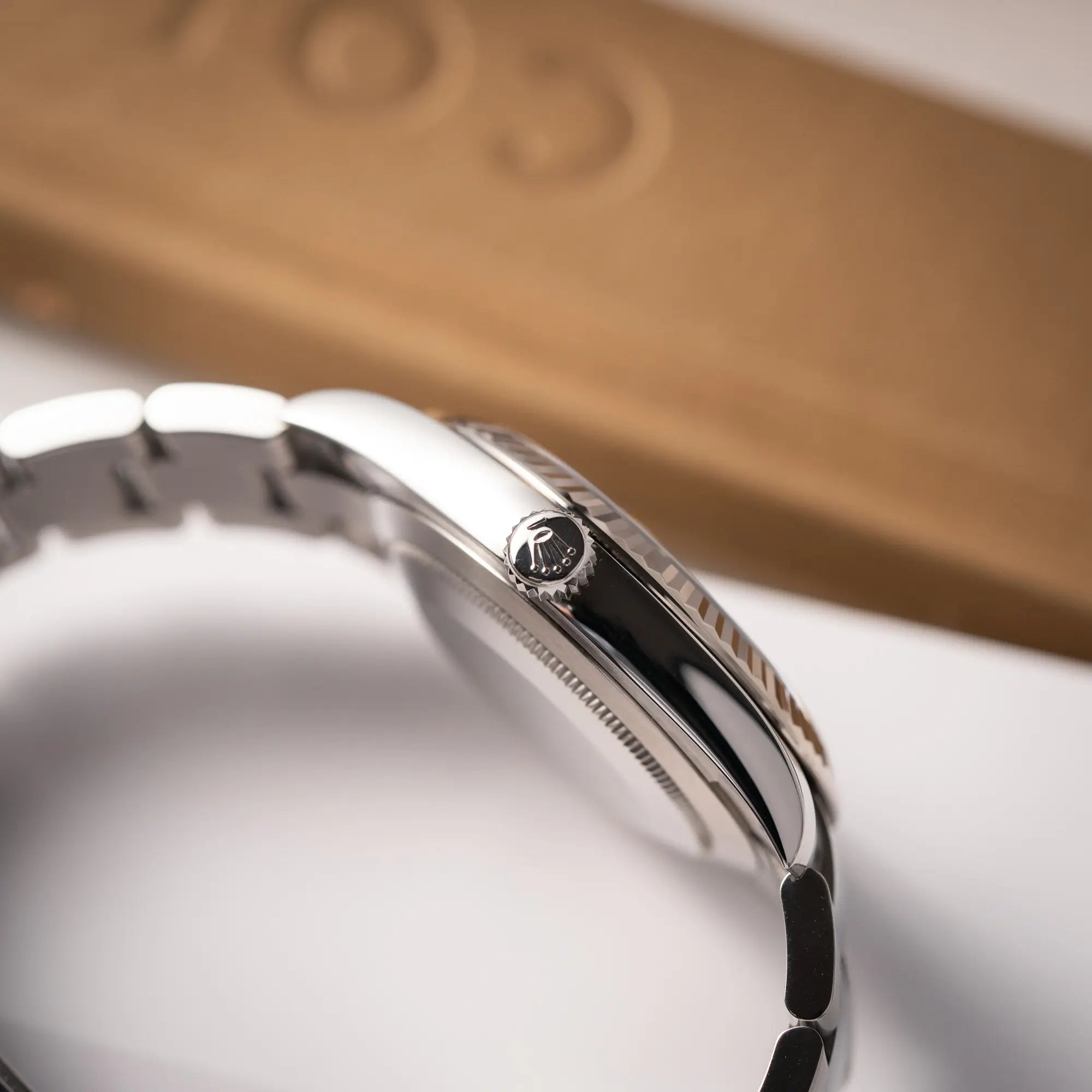 Produktfotografie zeigt die Aufzugskrone der Rolex Datejust 41 der Referenz 126334 mit geriffelter Weißgold-Lünette und Oyster-Stahlband mit dem grauen Wimbledon-Zifferblatt mit schwarz-grünen Indizes