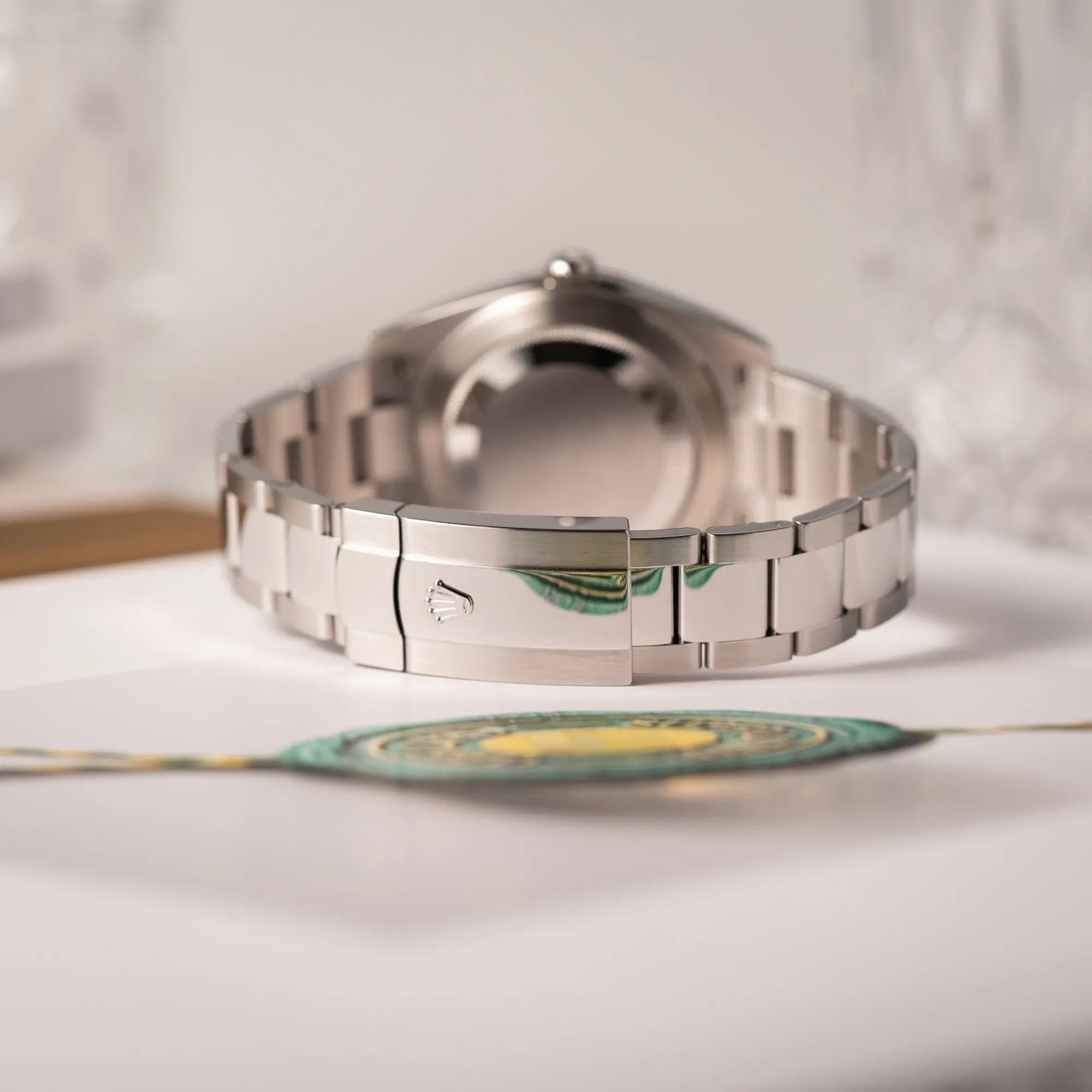 Produktfotografie zeigt das Oyster-Stahlband und die Oyster-Stahl-Faltschliesse der Rolex Datejust 41 der Referenz 126334 mit geriffelter Weißgold-Lünette mit dem grauen Wimbledon-Zifferblatt mit schwarz-grünen Indizes