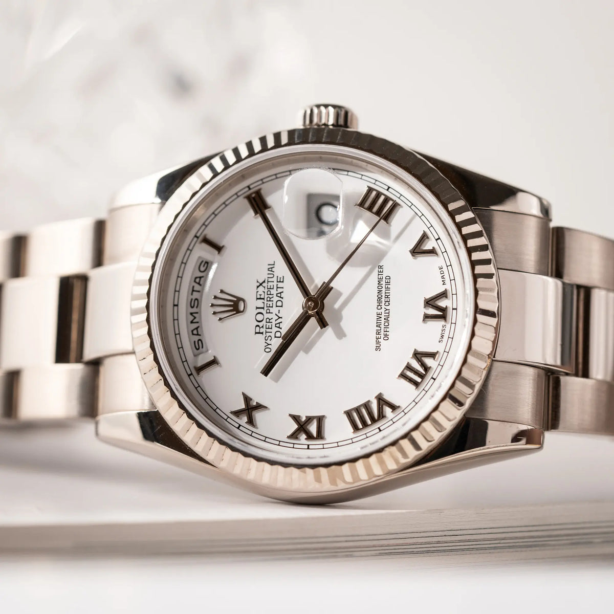 Detailaufnahme des Uhrenkopfes von der Rolex Day-Date 36 Armbanduhr in Weißgold der Referenz 118239 mit weißem Zifferblatt mit römischen Indizes am Oyster-Weißgold-Armband