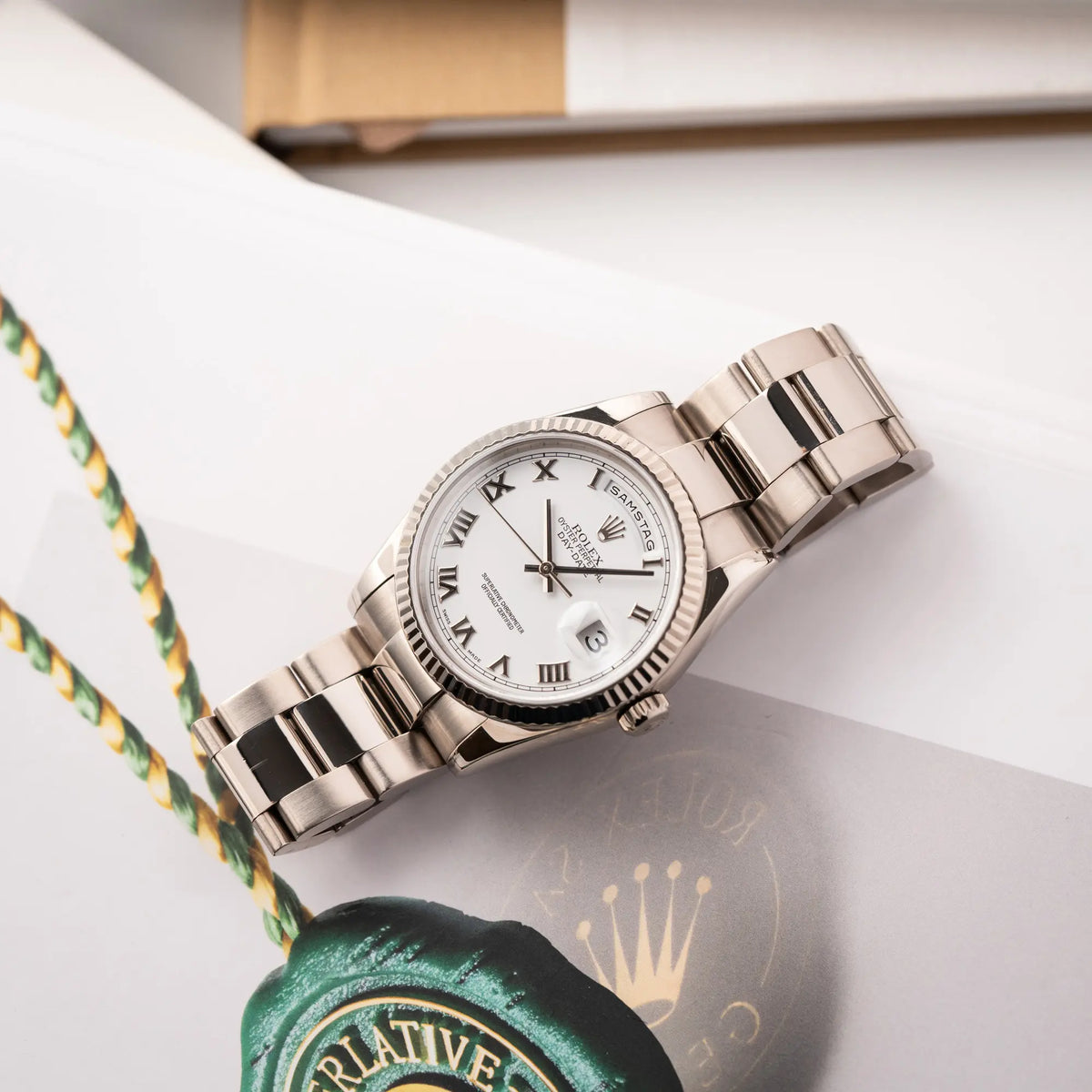 Rolex Day-Date 36 Armbanduhr in Weißgold der Referenz 118239 mit weißem Zifferblatt mit römischen Indizes am Oyster-Weißgold-Armband liegt auf einem Buch über Rolex-Uhren