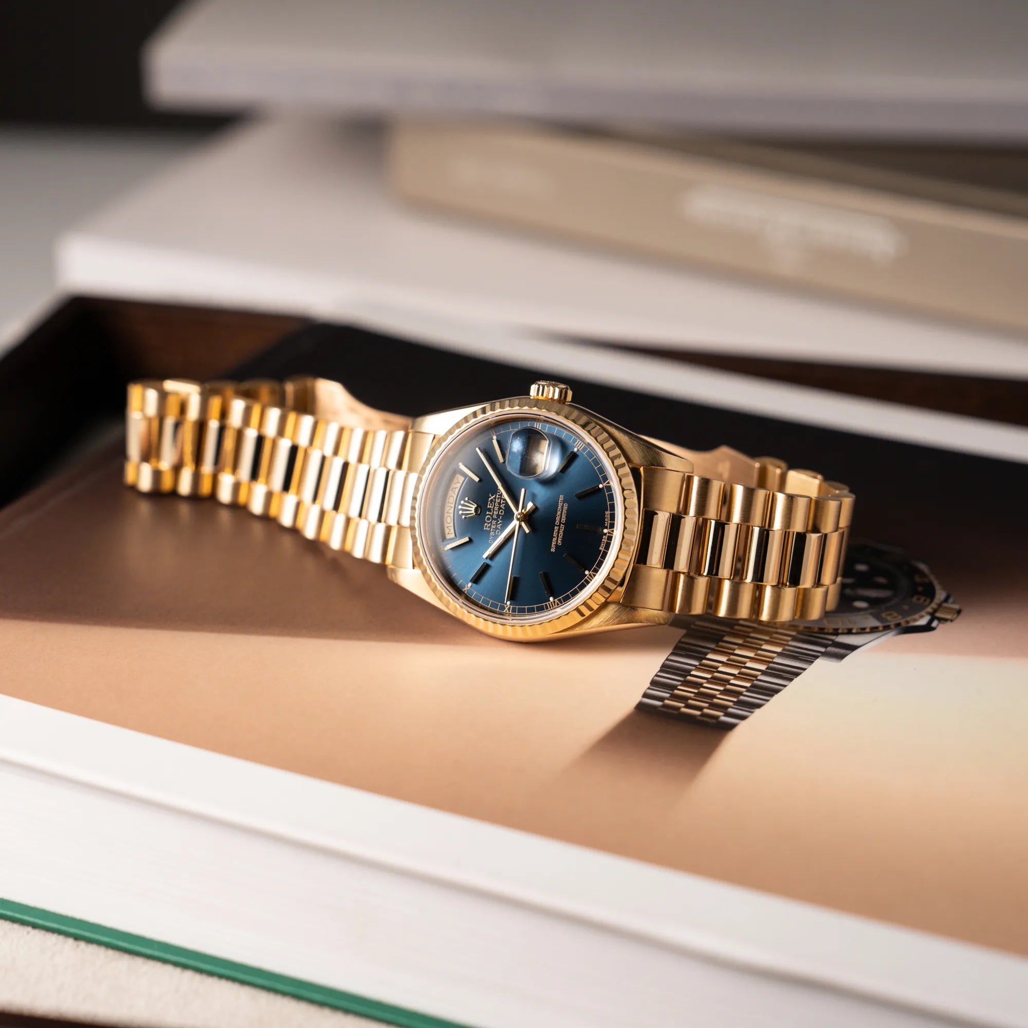 Produktfotografie der gelbgoldenen Rolex Day-Date 36 der Referenz 18238 mit blauem Zifferblatt und englisch-sprachiger Tagesanzeige