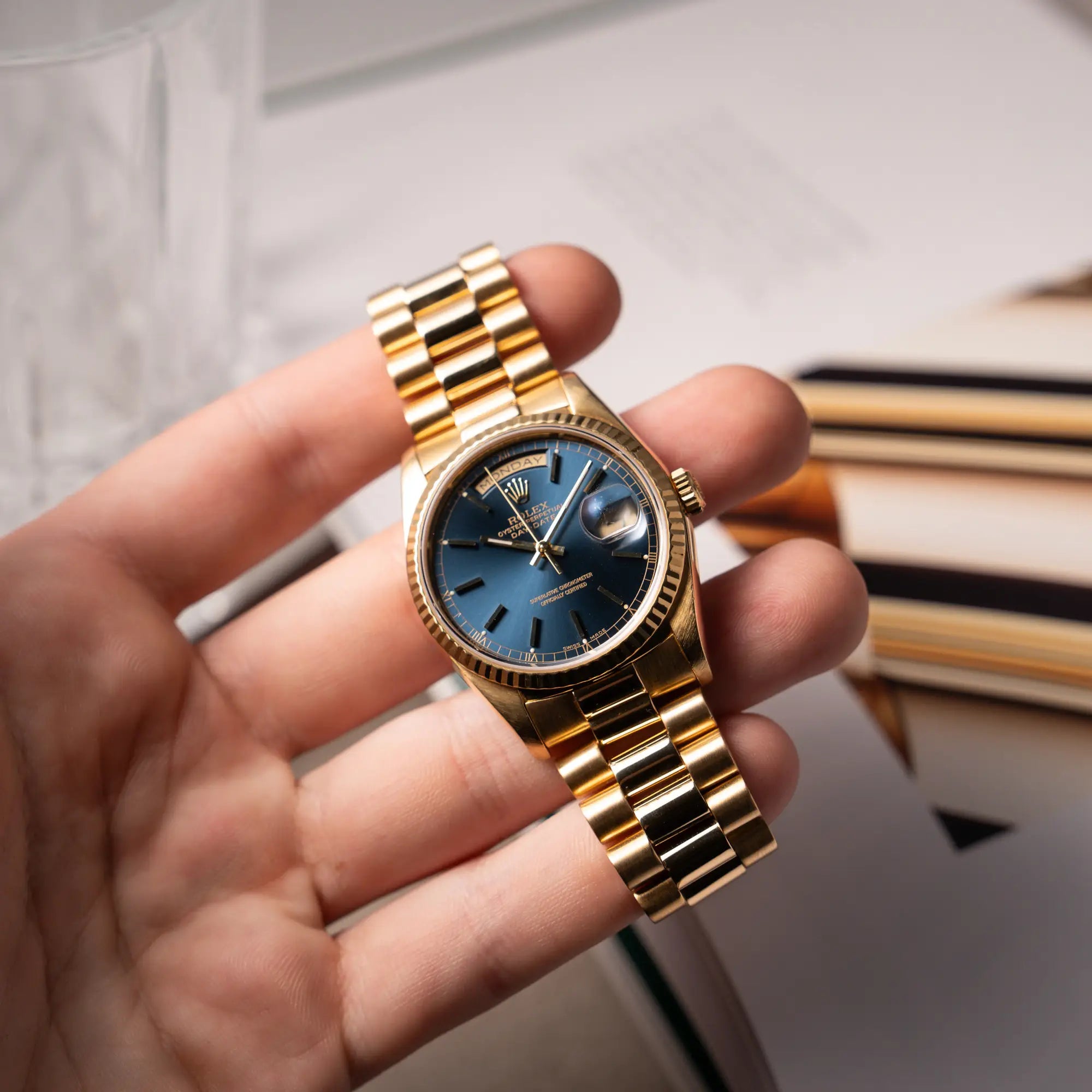 Mann hölt die der gelbgoldenen Rolex Day-Date 36 der Referenz 18238 mit blauem Zifferblatt und englisch-sprachiger Tagesanzeige in seiner Hand und präsentiert die Ihr in die Kamera