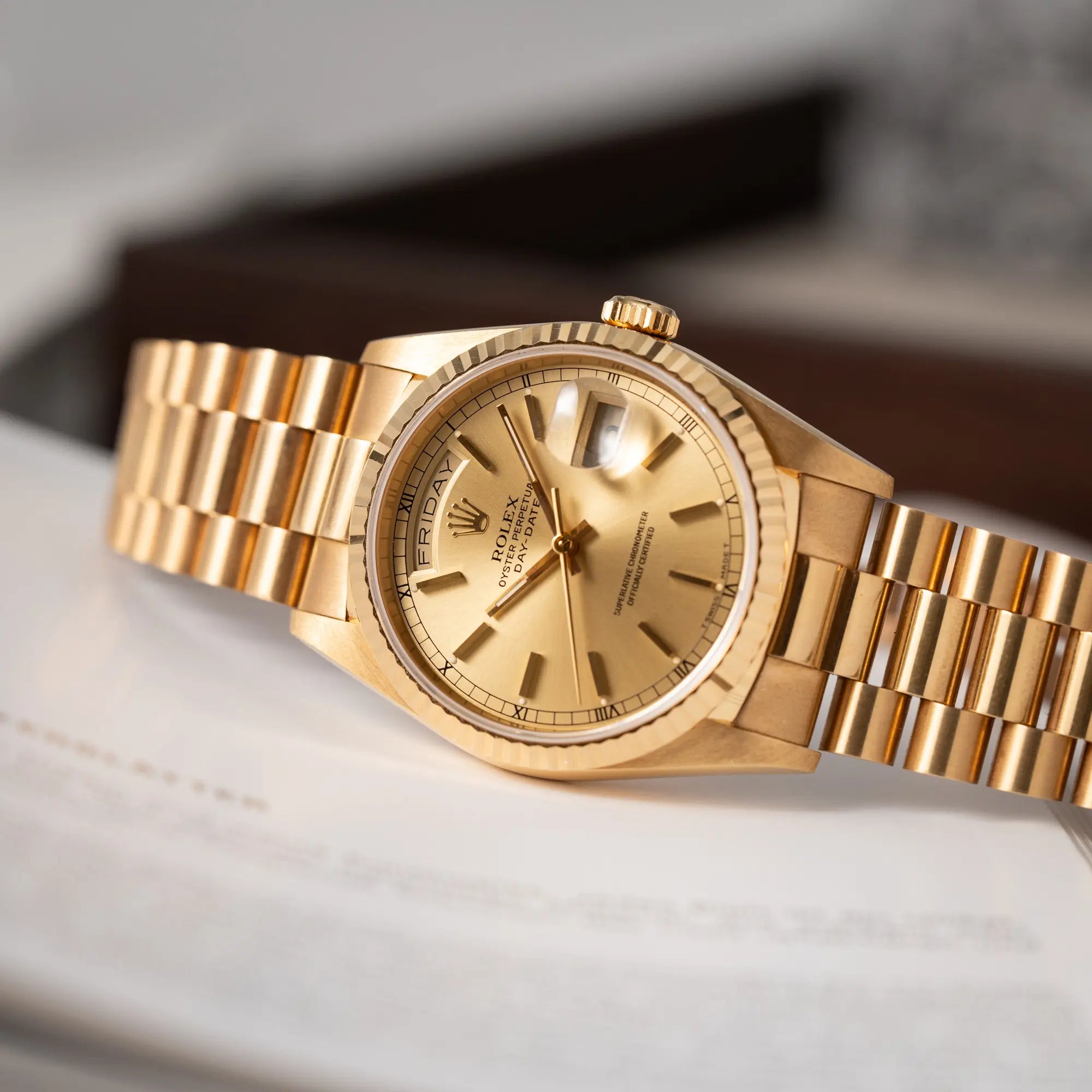 Produktfotografie der seitlich auf dem Uhrengehäuse liegenden Rolex Day-Date 36 der Referenz 18238 in Gelbgold mit champagnerfarbenem Stick-Dial