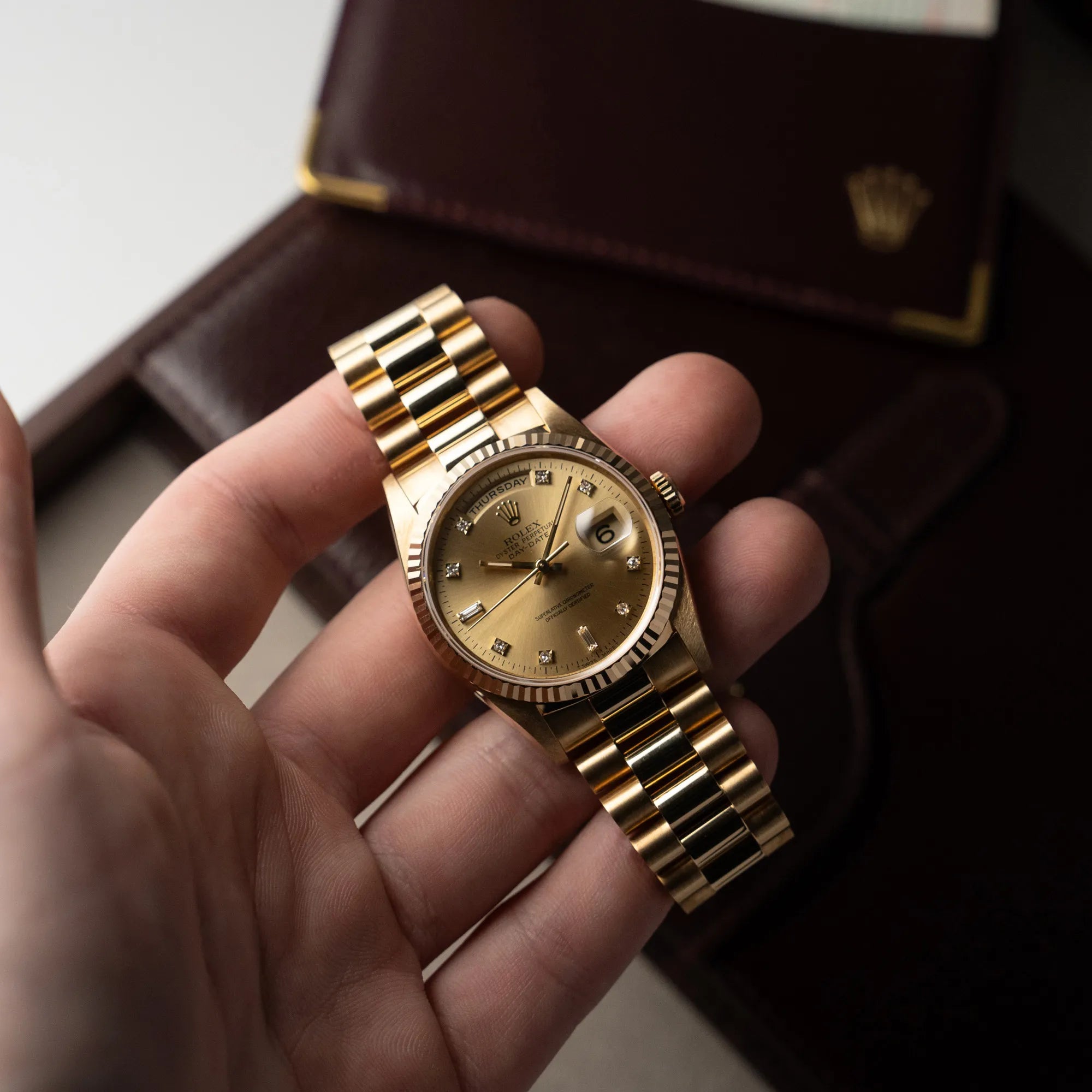 Mann hält die Rolex Day-Date 36 in Gelbgold (18238) mit Diamantzifferblatt der in einem neuwertigen Zustand in seiner Hand