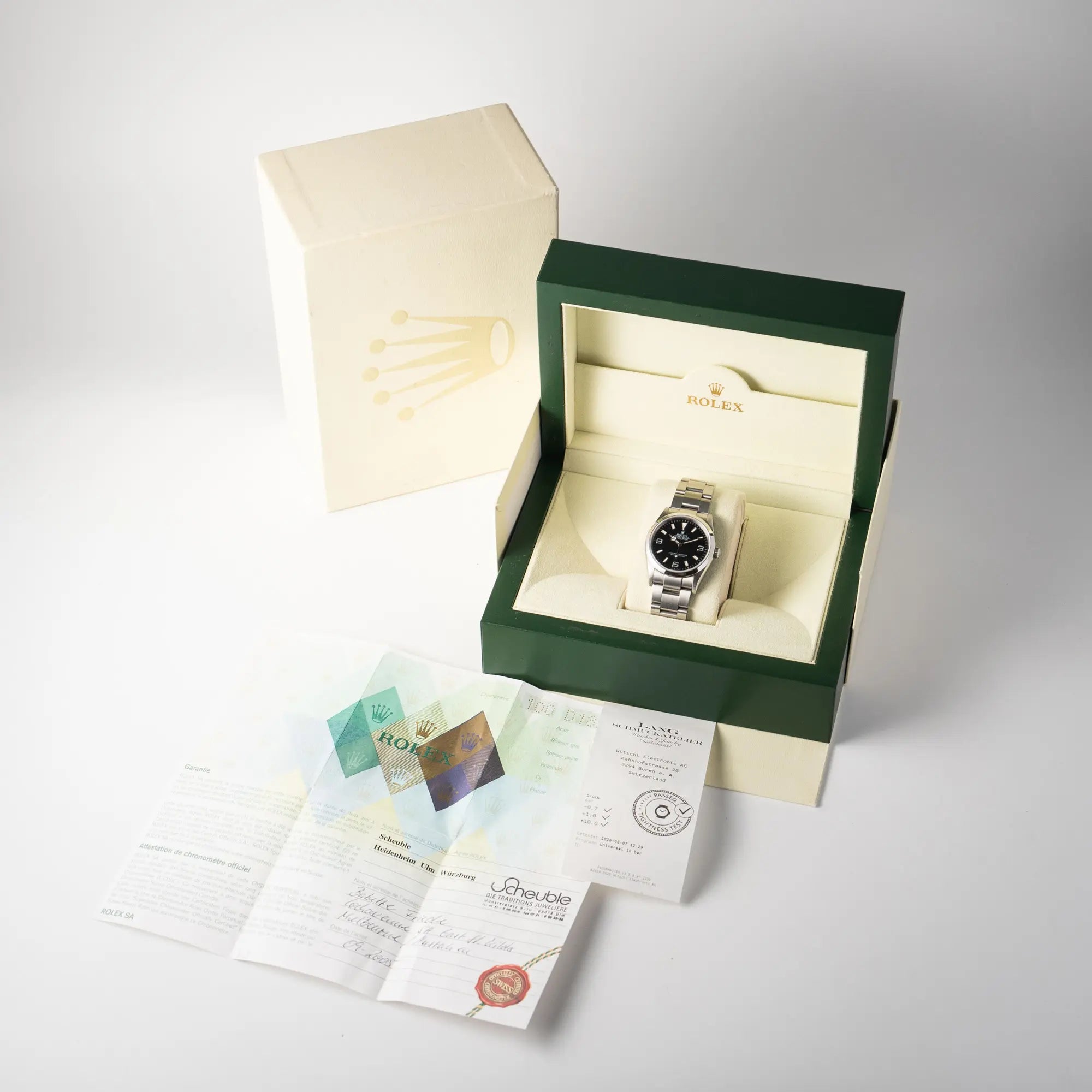 Lieferumfang zu der Rolex Explorer 36 der Referenz 114270 mit dem klassischen schwarzen 3-6-9-Explorer-Zifferblatt am Oyster-Stahlband, bestehend aus Box mit Umkarton, original Papieren und Wasserdichtheitstes