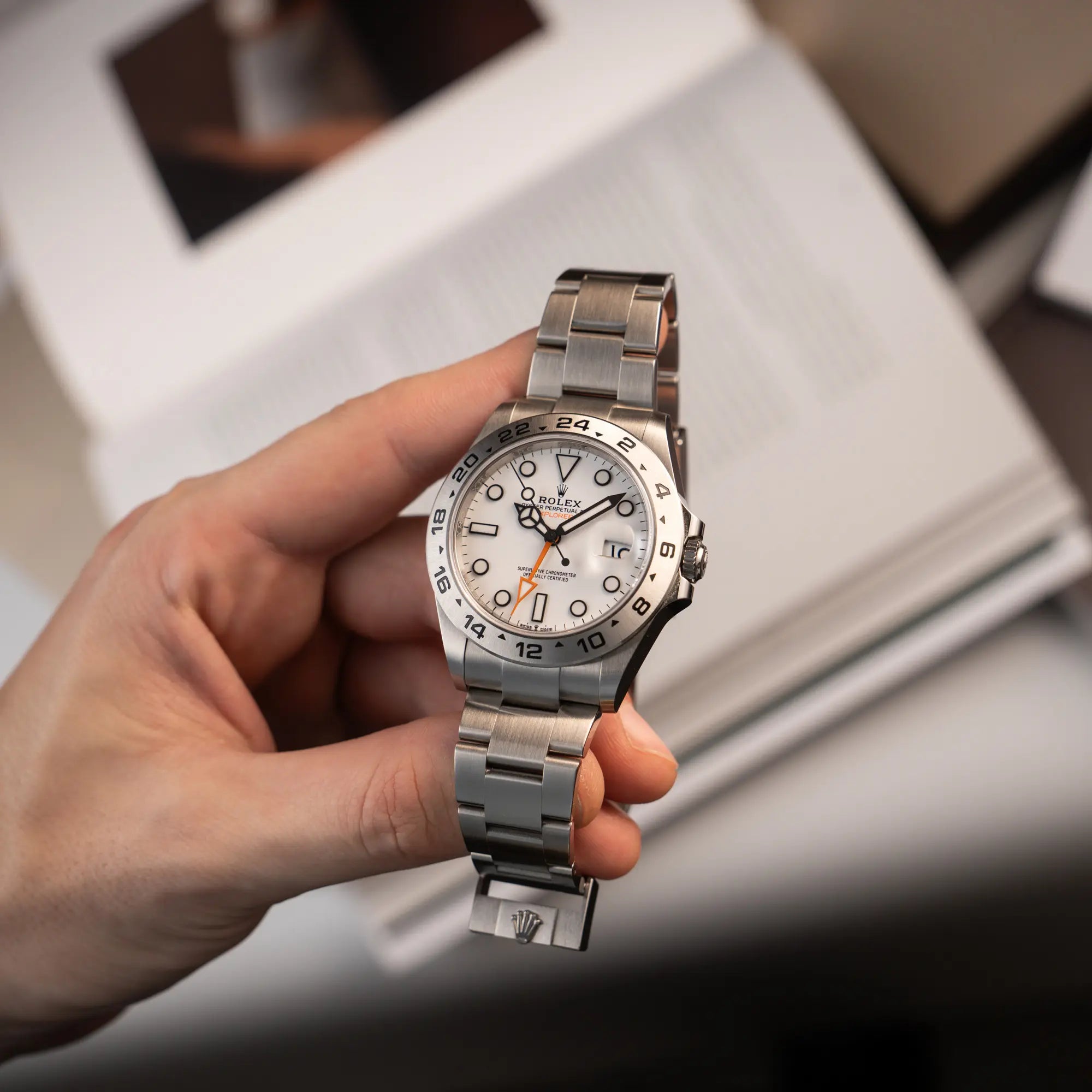 Mann hält die Rolex Explorer 2 der Referenz 226570 mit dem Polar Zifferblatt und orangem GMT-Zeiger in seiner Hand und präsentiert die Armbanduhr in die Kamera