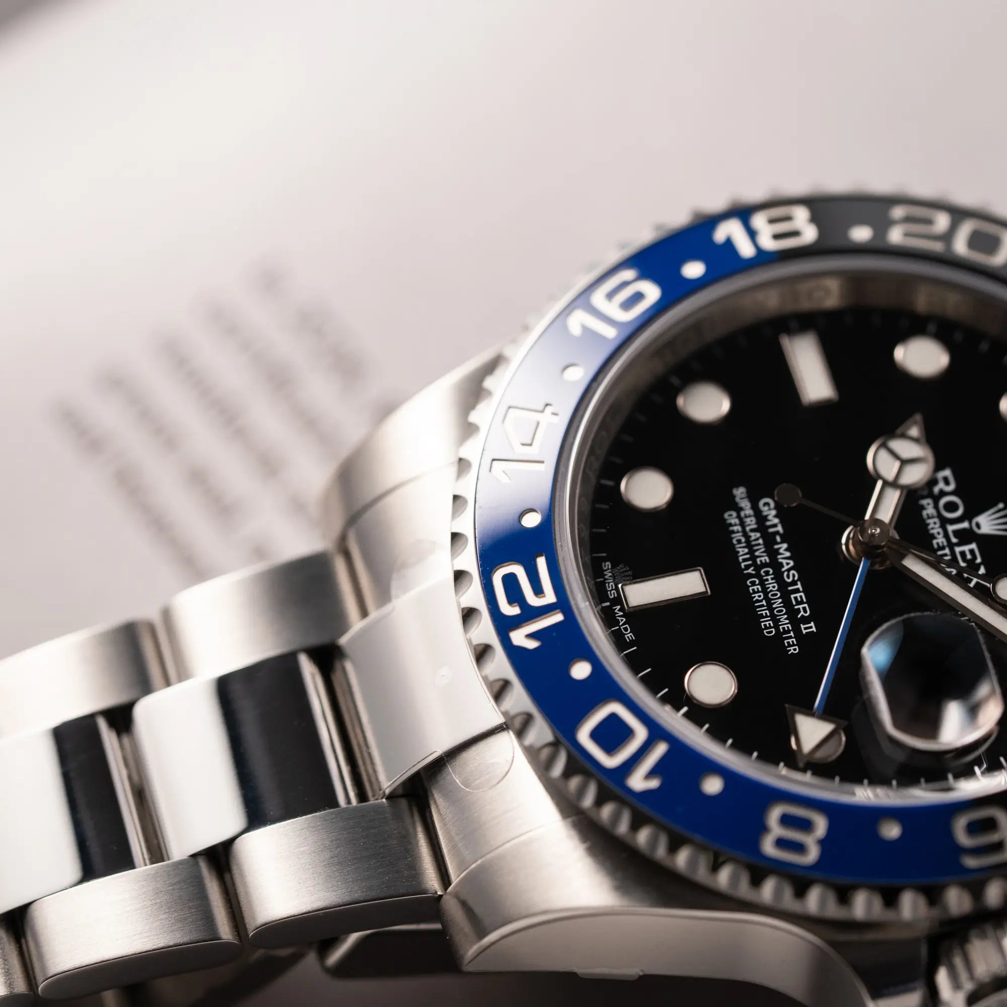 Detailaufnahme der Rolex GMT-Master II der Referenz 116710BLNR mit dem Nickname "Batman" mit der schwarz blauen Keramik-Lünette am Oyster-Stahlband im verklebten Neuzustand mit Fokus auf dem blauen Lünetten-Abschnitt
