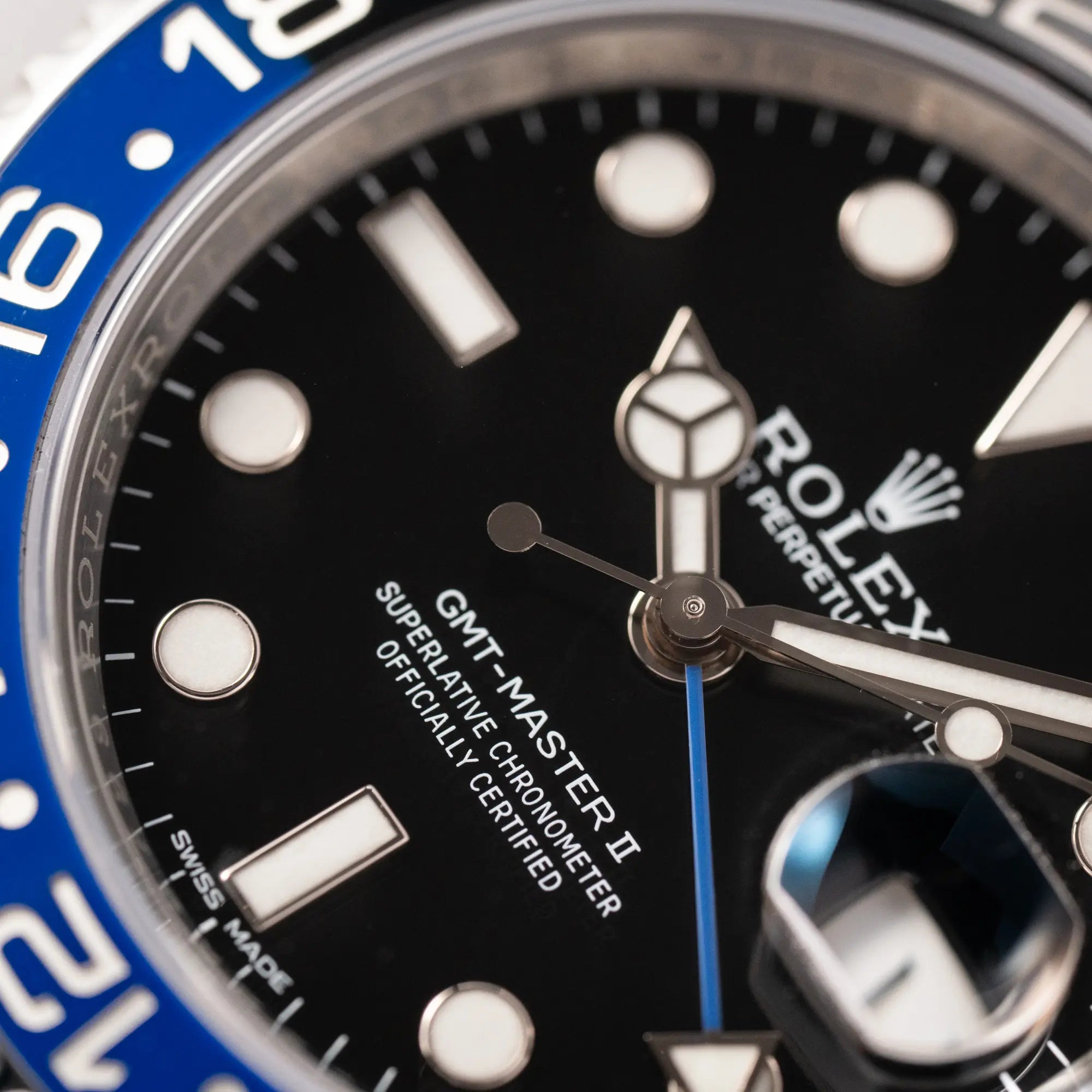 Makro-Aufnahme des Zifferblatts und Zeigersatzes der Rolex GMT-Master II der Referenz 116710BLNR mit dem Nickname "Batman" mit der schwarz blauen Keramik-Lünette am Oyster-Stahlband im verklebten Neuzustand