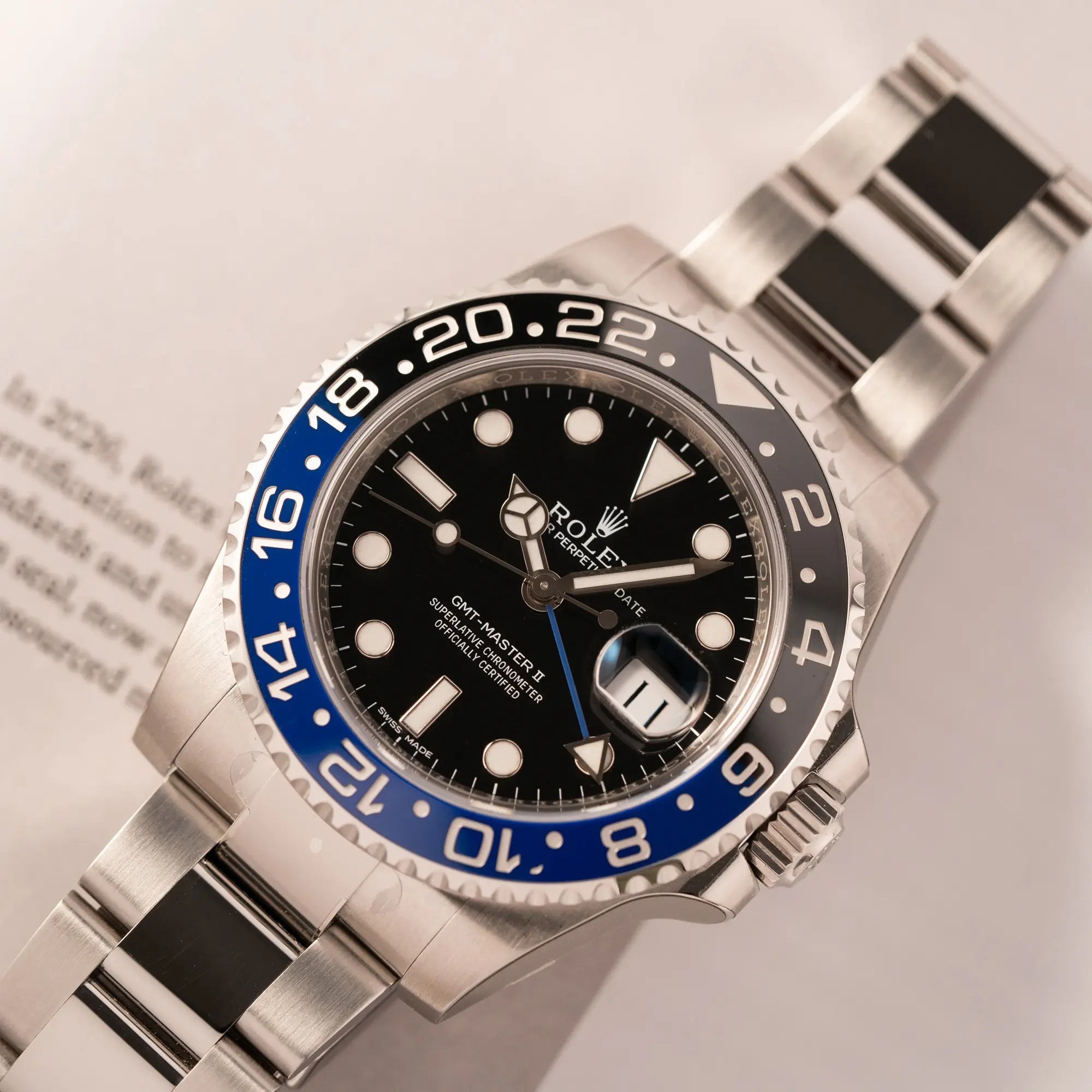 Produktfotografie zeigt die Rolex GMT-Master II der Referenz 116710BLNR mit dem Nickname "Batman" mit der schwarz blauen Keramik-Lünette am Oyster-Stahlband im verklebten Neuzustand