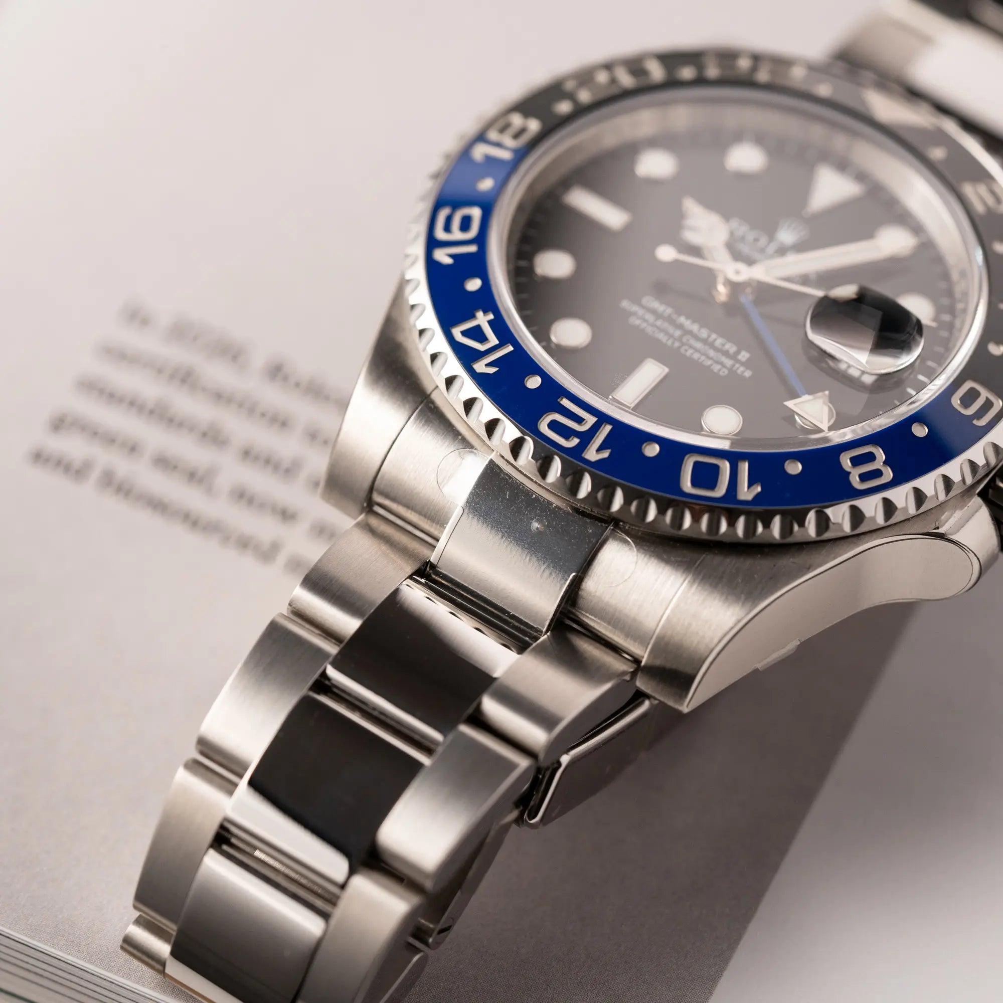 Detailaufnahme des Bandanstoßes mit Sticker von der Ausliegerung von der Rolex GMT-Master II der Referenz 116710BLNR mit dem Nickname "Batman" mit der schwarz blauen Keramik-Lünette am Oyster-Stahlband im verklebten Neuzustand