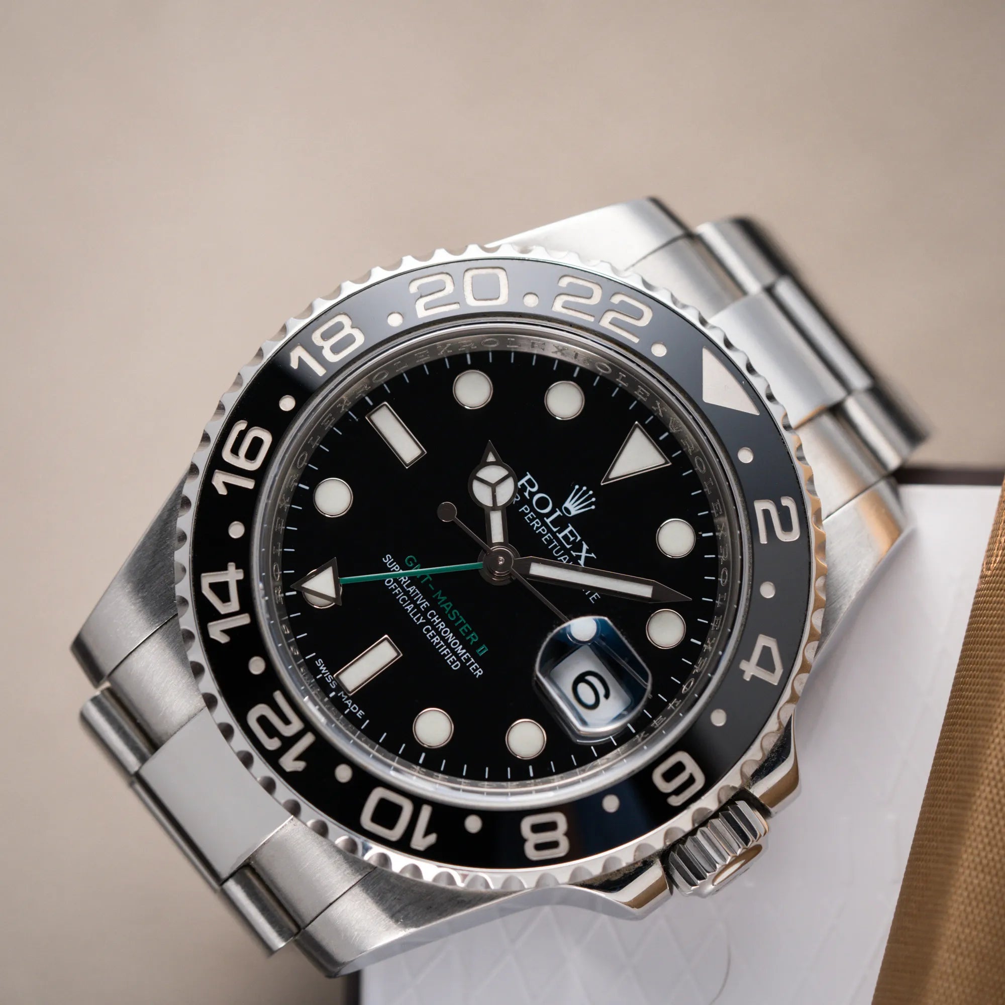 Detailaufnahme des Uhrenkopfes der Rolex GMT-Master II 116710LN mit schwarzer Keramik-Lünette und dem typischen grünem GMT-Zeiger aus der Vogelperspektive