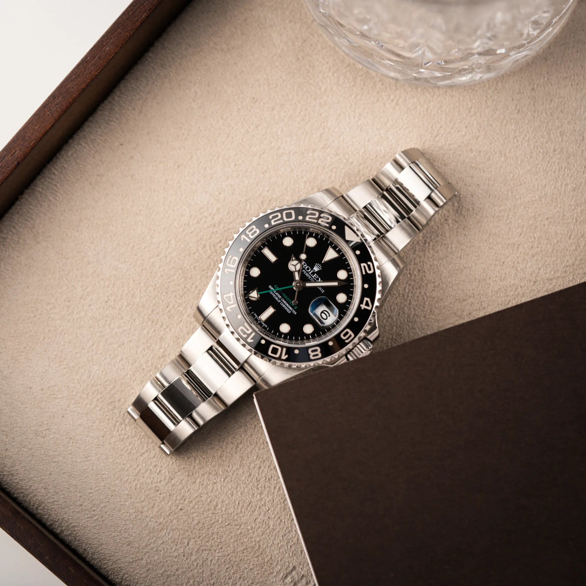 Rolex GMT-Master II 116710LN mit schwarzer Keramik-Lünette und dem typischen grünem GMT-Zeiger liegt auf Juwelierstablet