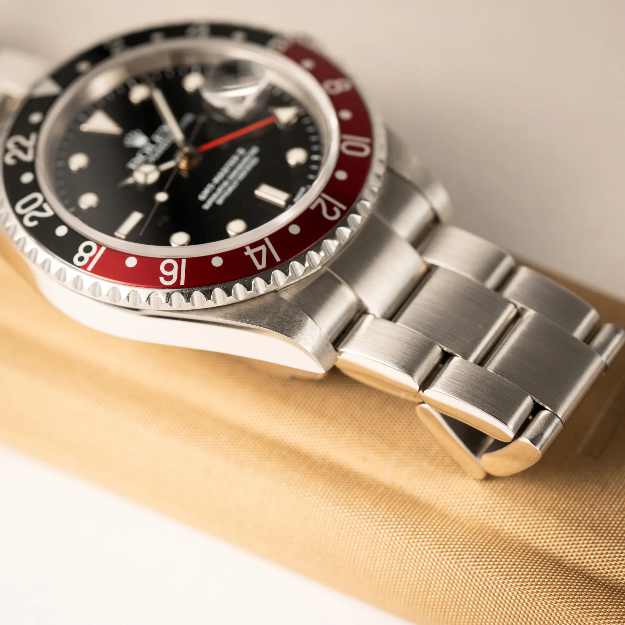 Produktfotografie der Rolex GMT-Master II 16710 mit der schwarz-roten "Coke" Aluminium-Lünetten-Einlage aus 2003 am Oyster Stahlband zeigt den Zustand des Bands und der Bandanstoße