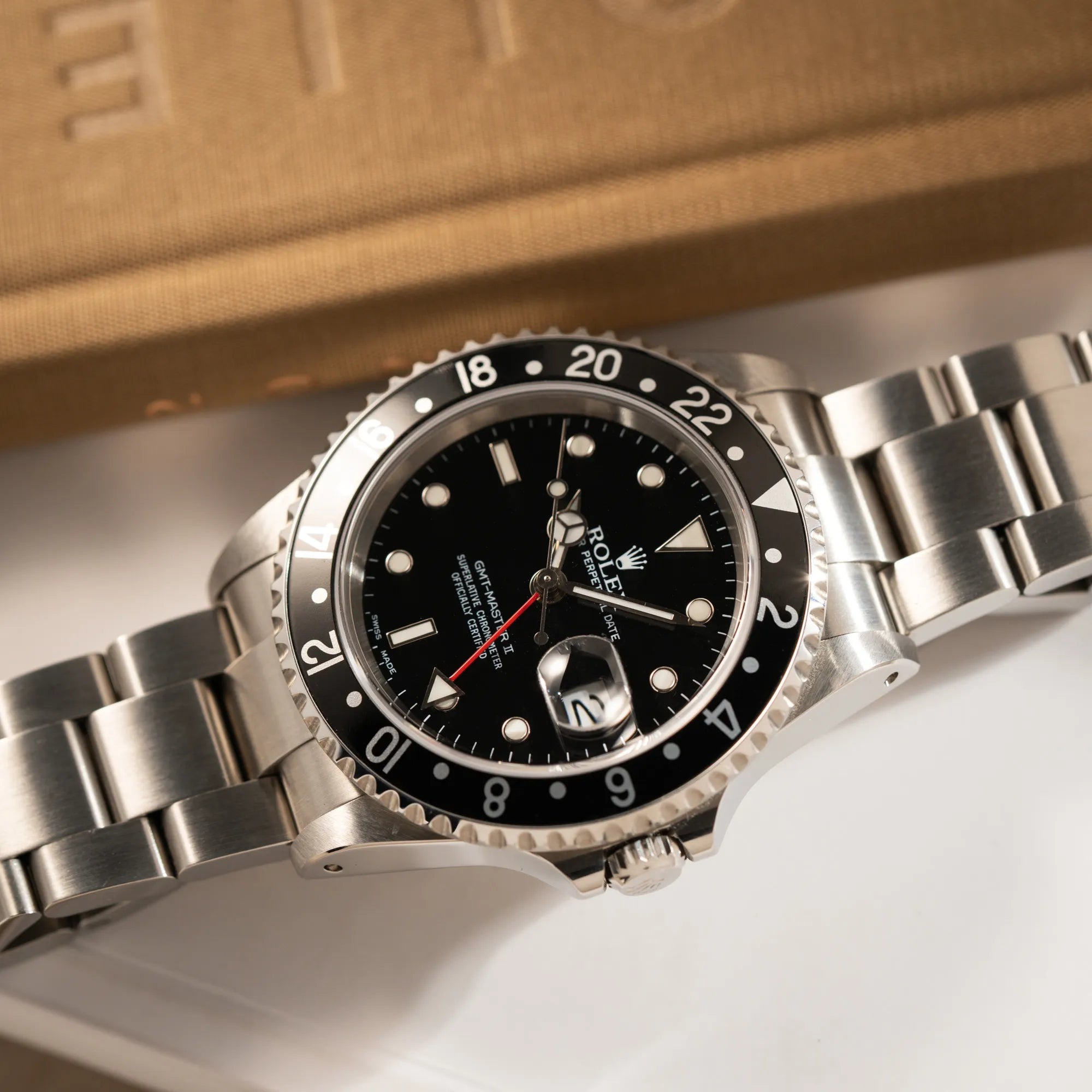 Produktfotografie der flach auf dem Uhrenarmband liegenden Rolex GMT-Master II 16710 aus 2001 mit schwarzem Aluminium-Lünetten-Inlay in einem neuwertigen Zustand