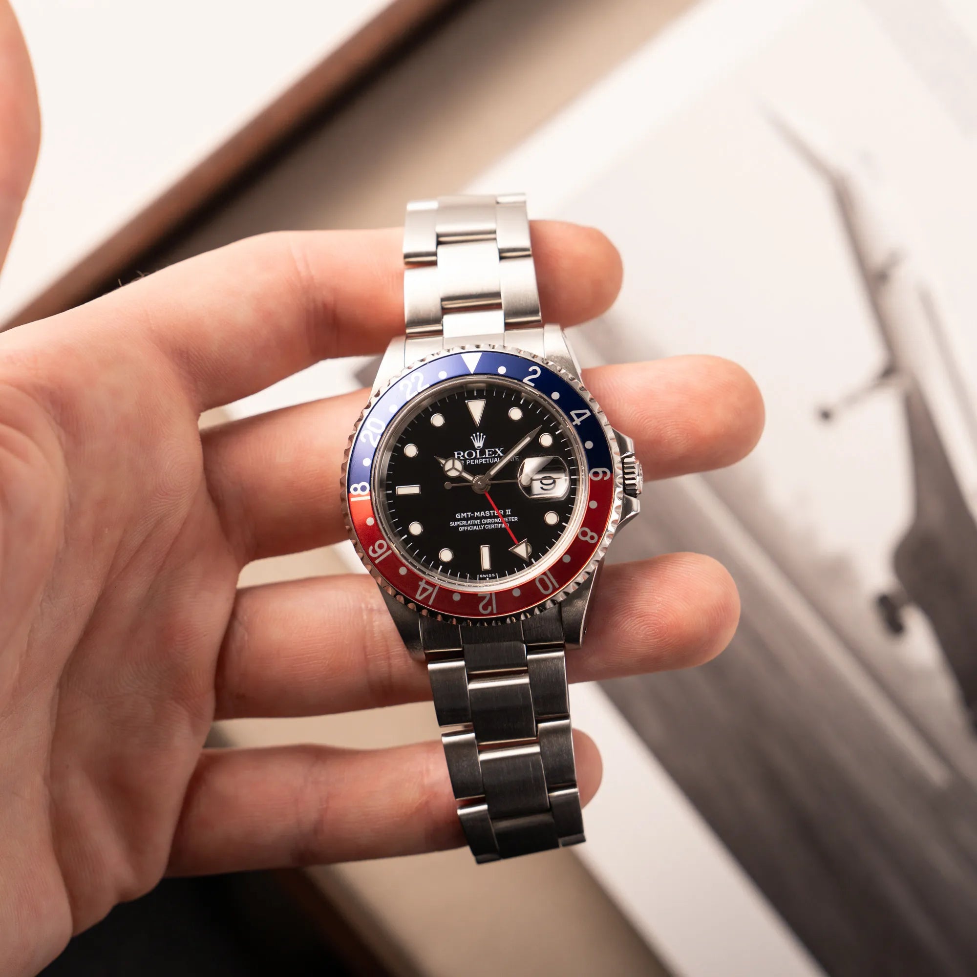 Mann hält die Rolex GMT-Master II 16710 mit blaue-roter Pepsi-Lünette aus 1998 in seiner Hand und präsentiert die Uhr in die Kamera