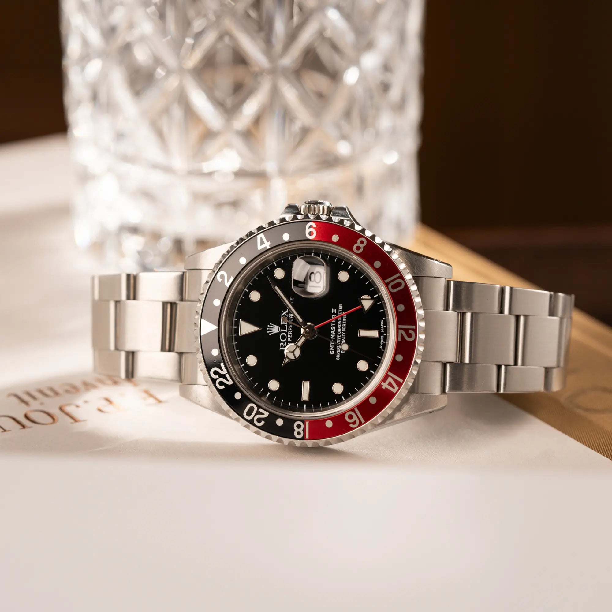 Produktfotografie der seitlich liegenden Rolex GMT-Master II 16710 in Edelstahl mit schwarz-roten "Coke" Lünetten-Inlay
