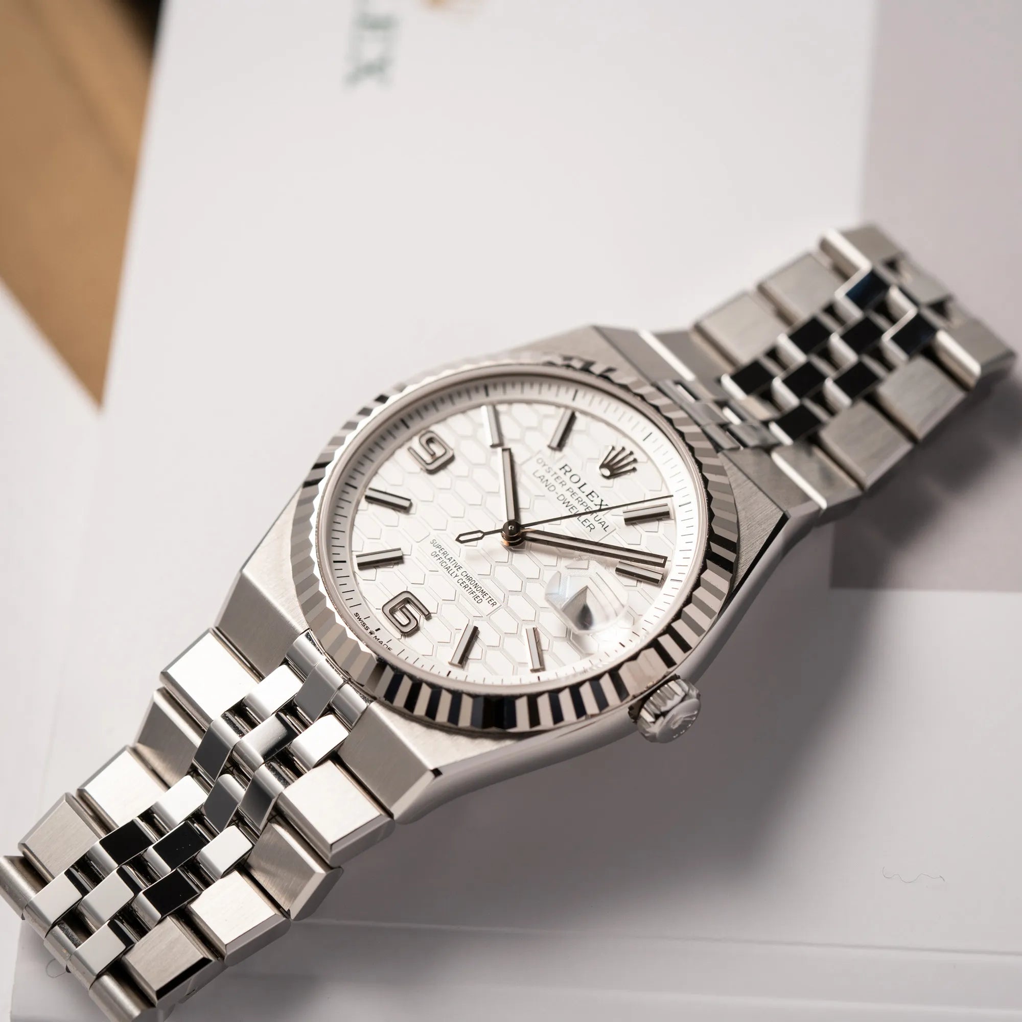 Produktfoto für die Rolex Land-Dweller 40 der Referenz 127334 im neuwertigen Zustand mit dem weißen Zifferblatt in Waben-Struktur am neuen Flat-Jubilee-Armband