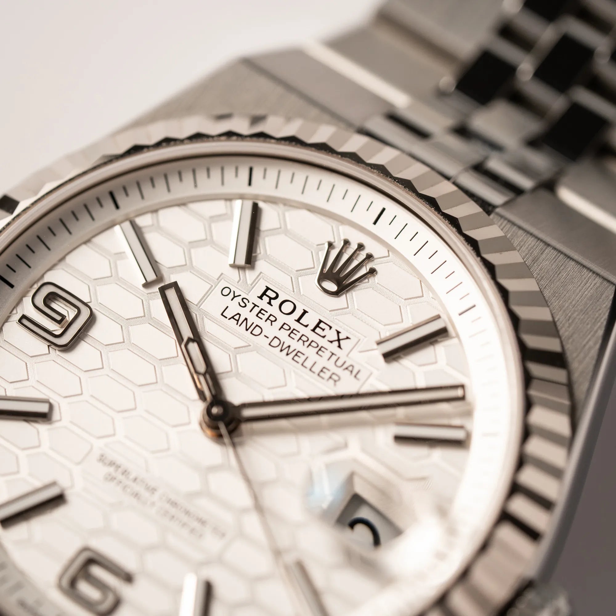 Detailaufnahme der Rolex Krone bei 12 Uhr von der Rolex Land-Dweller 40 der Referenz 127334 im neuwertigen Zustand mit dem weißen Zifferblatt in Waben-Struktur am neuen Flat-Jubilee-Armband