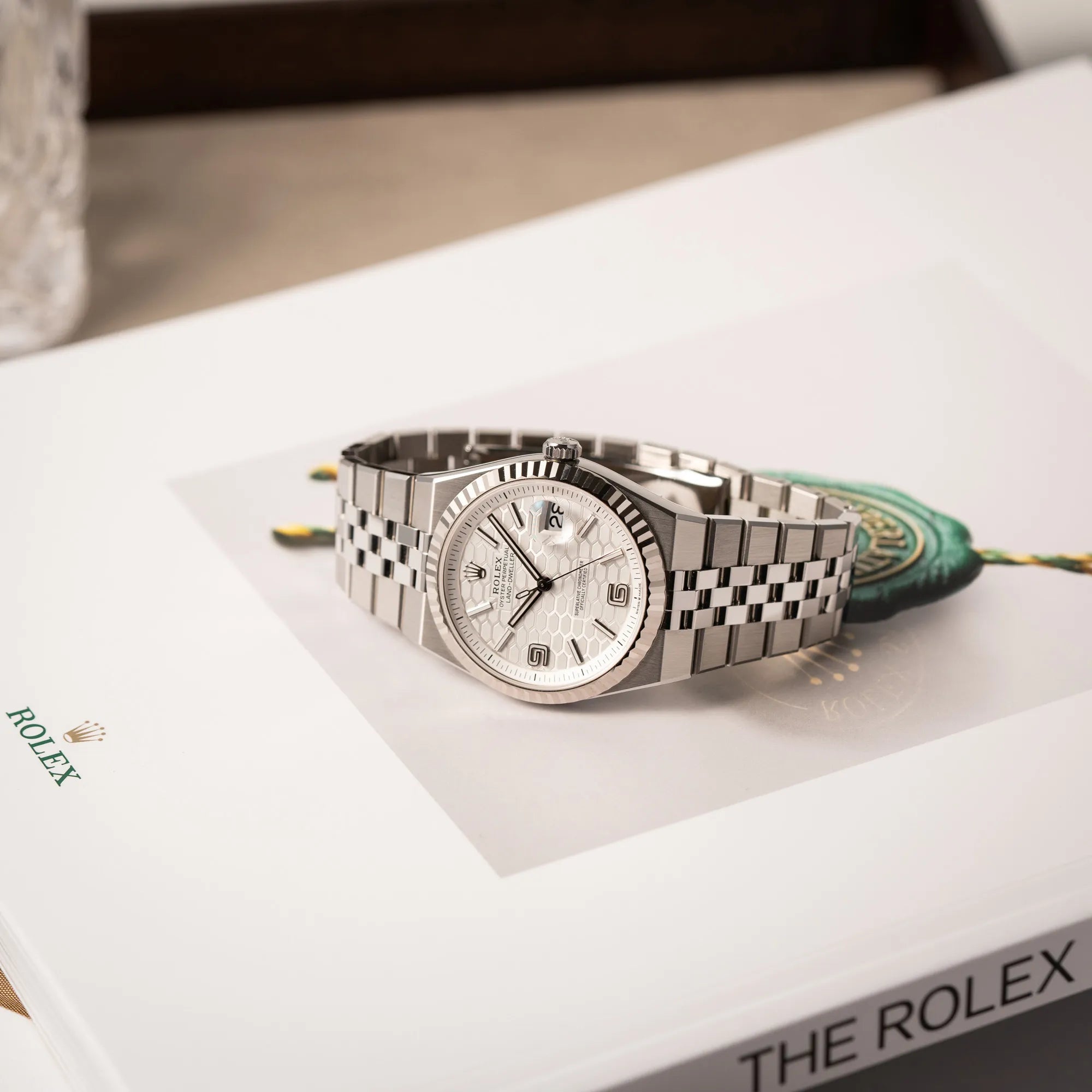 Produktfotografie für die Rolex Land-Dweller 40 der Referenz 127334 im neuwertigen Zustand mit dem weißen Zifferblatt in Waben-Struktur am neuen Flat-Jubilee-Armband