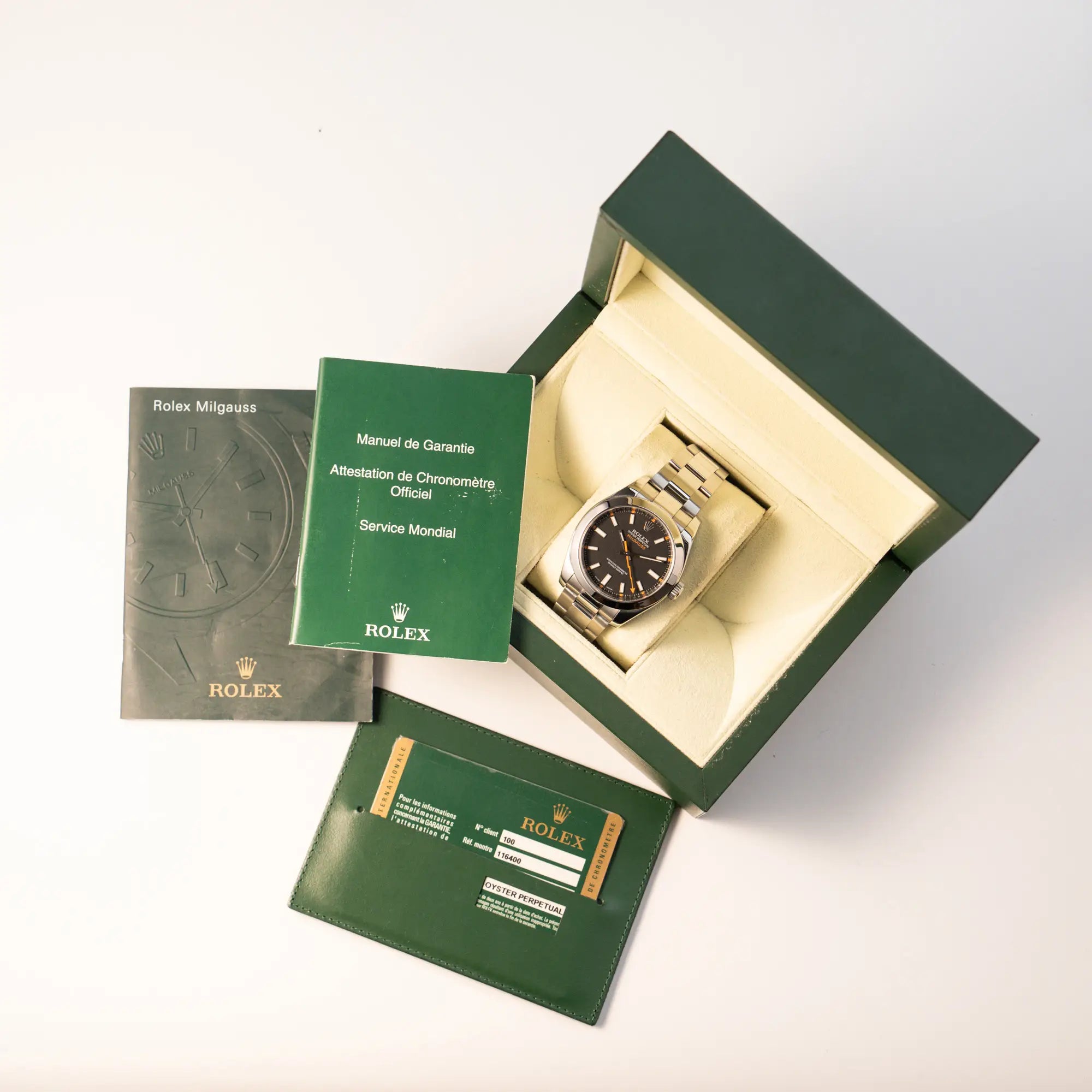 Rolex Milgauss der Referenz 116400 mit schwarzem Zifferblatt und orangen Akzenten zusammen mit dem Lieferumfang, bestehend aus Box, Papieren und Booklets