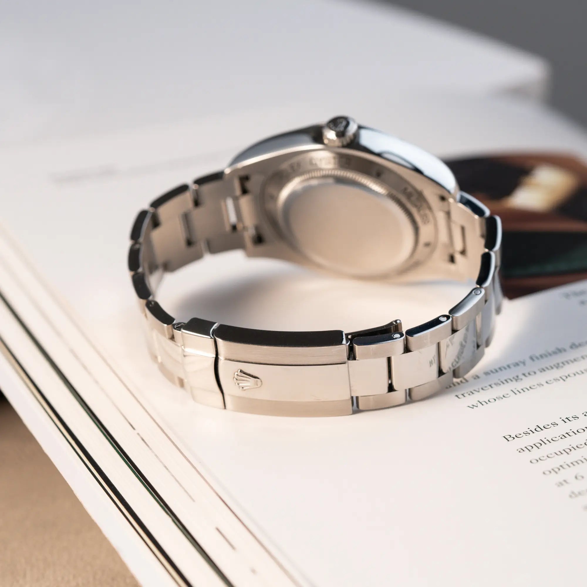 Produktfotografie der Rolex Milgauss der Referenz 116400 mit schwarzem Zifferblatt und orangen Akzenten zeigt die geschlossene Oyster-Faltschiesse