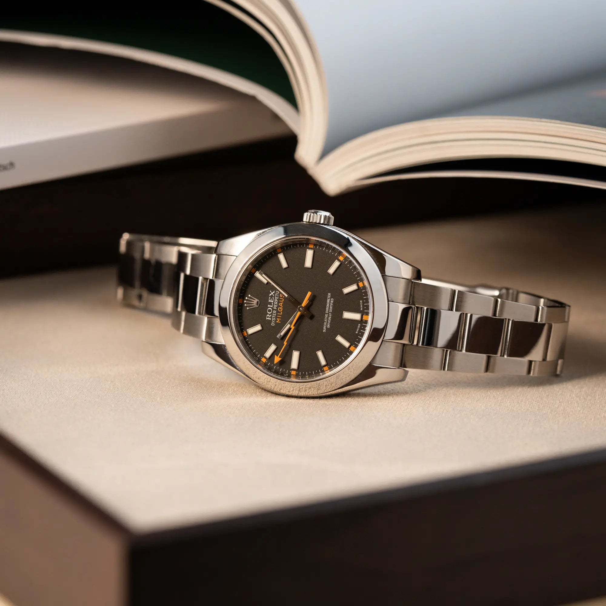 Produktfotgrafie der Rolex Milgauss der Referenz 116400 mit schwarzem Zifferblatt und orangen Akzenten auf Juwelierstablet