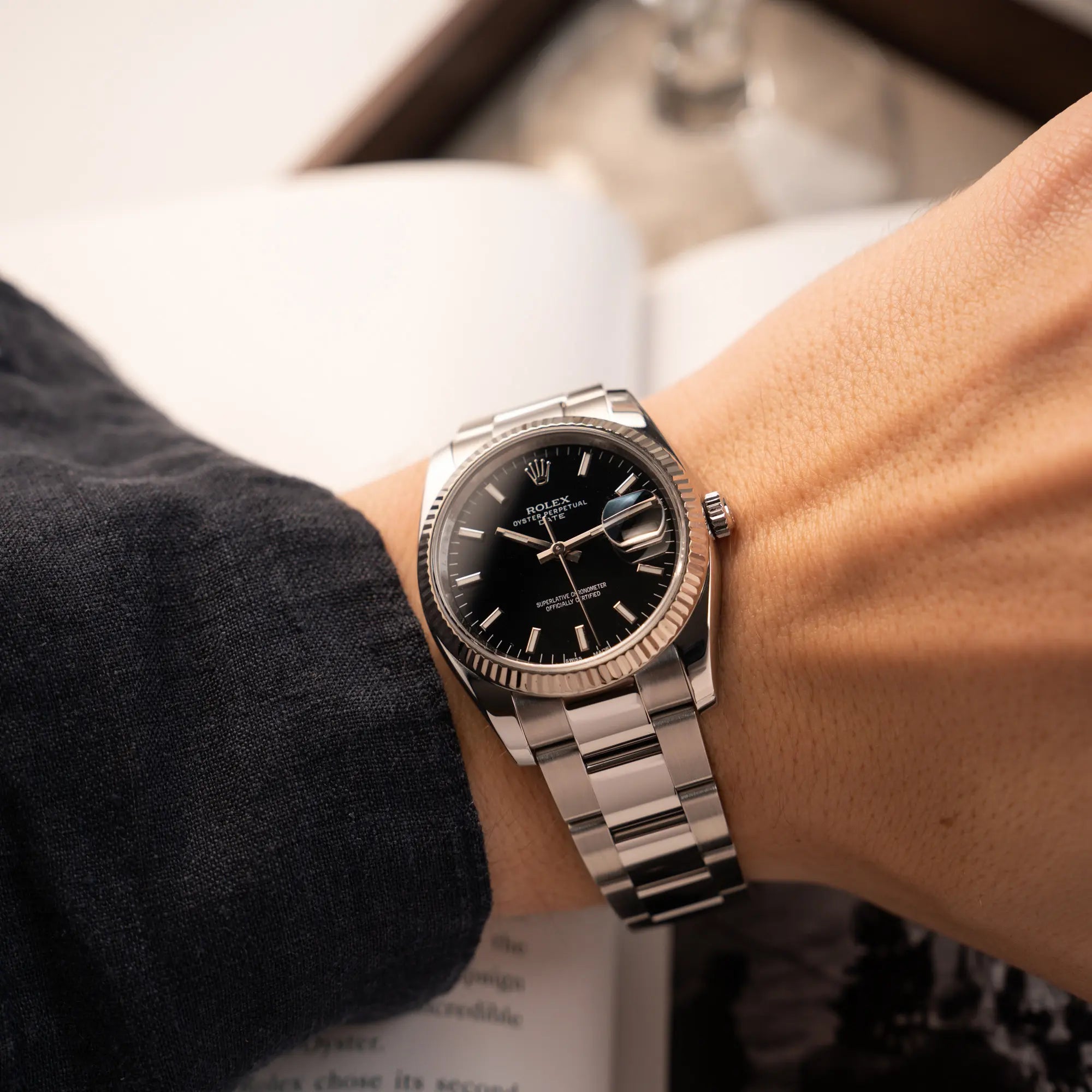 Mann trägt die Rolex Oyster Perpetual Date 34 der Referenz 115234 mit schwarzem Zifferblatt und der geriffelten Weißgold-Lünette an seinem Arm