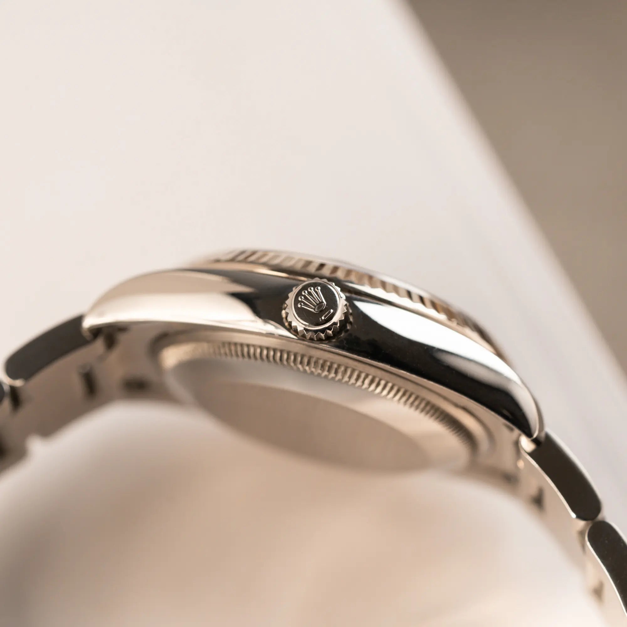 seitliche Gehäuseflanke der Rolex Oyster Perpetual Date 34 der Referenz 115234 mit schwarzem Zifferblatt und der geriffelten Weißgold-Lünette mit Blick auf die Aufzugskrone