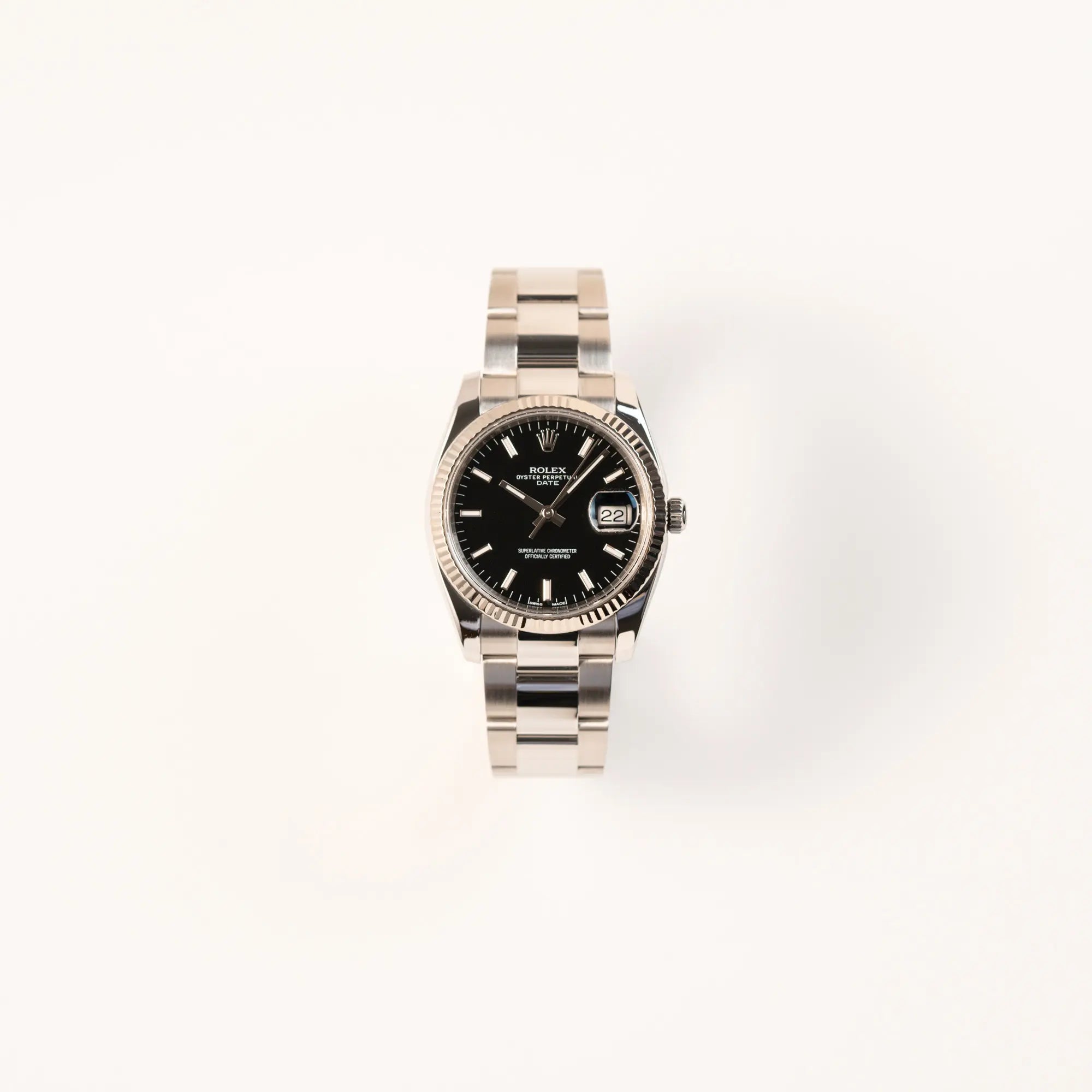 Frontale Ansicht der Rolex Oyster Perpetual Date 34 der Referenz 115234 mit schwarzem Zifferblatt und der geriffelten Weißgold-Lünette