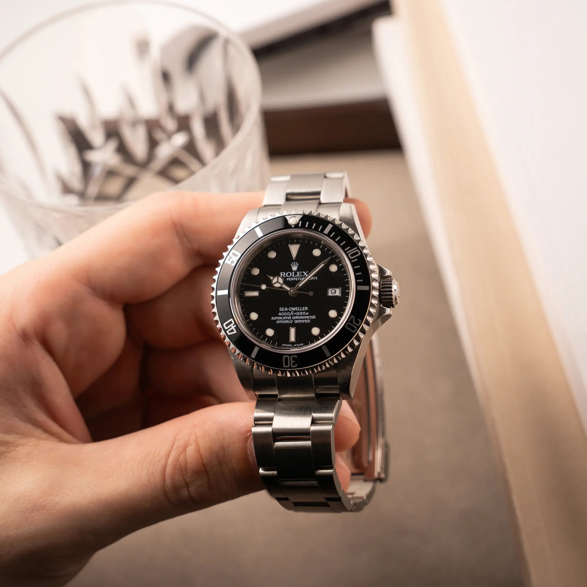 Mann hält die Rolex Sea-Dweller 4000 in schwarz der Referenz 16600 mit typischen kleinem Datumsfenster in seiner Hand