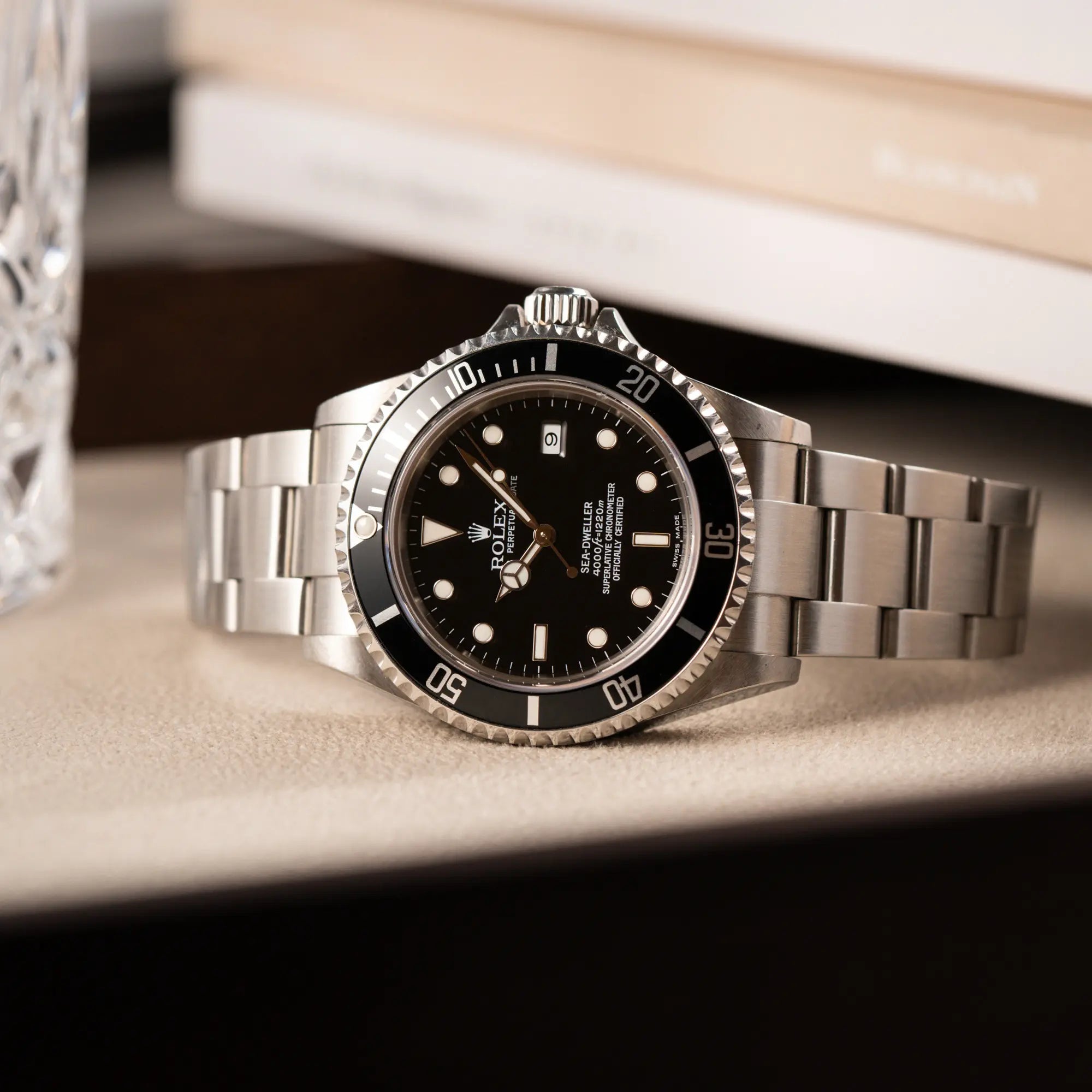 Produktfotografie der seitlich auf dem Gehäuse liegenden Rolex Sea-Dweller 4000 in schwarz der Referenz 16600 mit typischen kleinem Datumsfenster