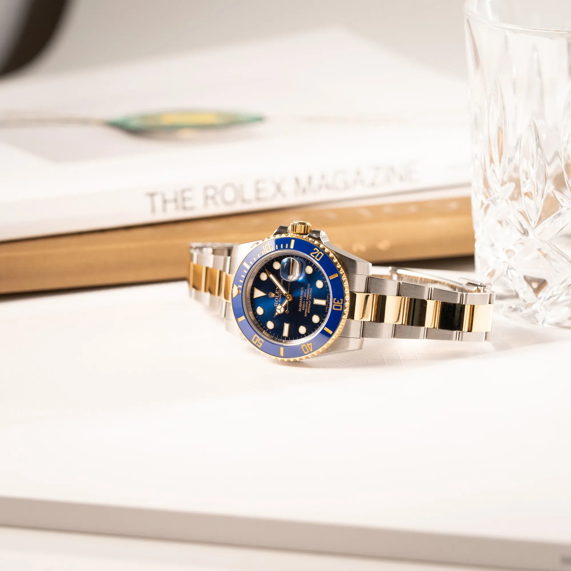 Rolex Submariner Date der Referenz 116613LB in Stahl-Gold mit blauem Zifferblatt - auch mit Nickname Bluesy bennant - am passenden Oytser-Armband in Stahl-Gold liegt seitlich auf dem Uhrengehäuse