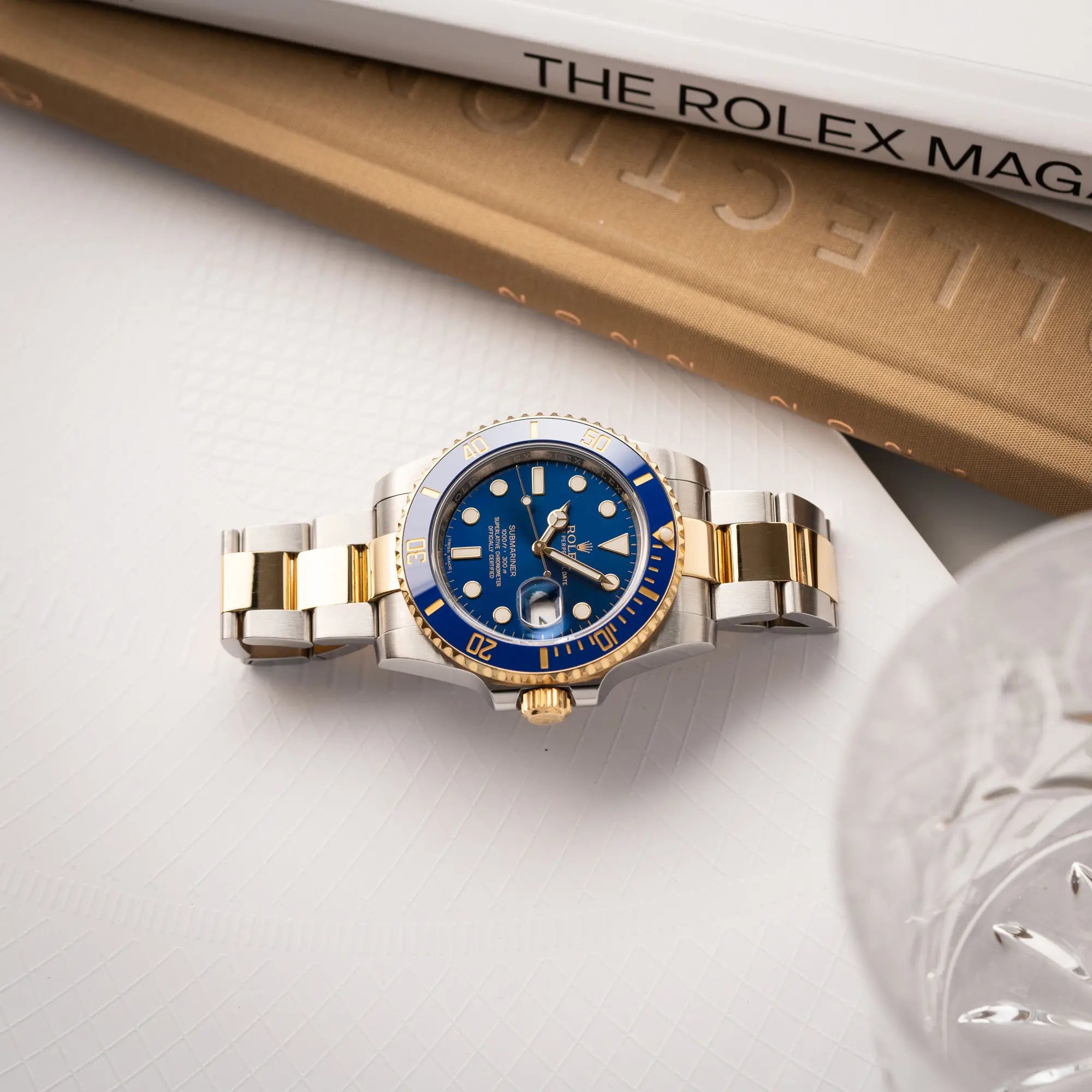 Rolex Submariner Date der Referenz 116613LB in Stahl-Gold mit blauem Zifferblatt - auch mit Nickname Bluesy bennant - am passenden Oytser-Armband in Stahl-Gold liegt flach auf einem Buch