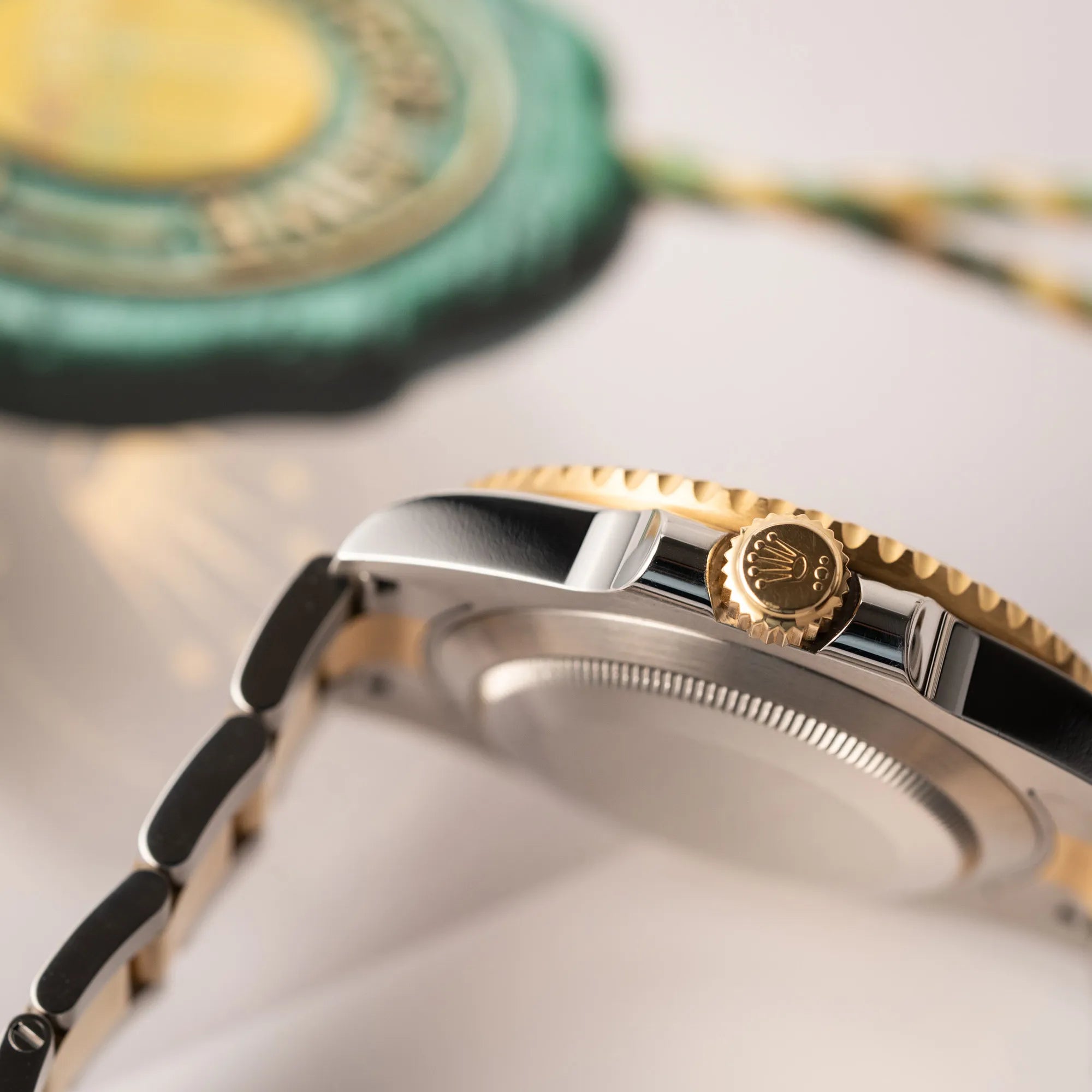 Produktfotografie der Rolex Submariner Date der Referenz 116613LB in Stahl-Gold mit blauem Zifferblatt - auch mit Nickname Bluesy bennant - am passenden Oytser-Armband in Stahl-Gold zeigt die seitliche Gehäuseflanke mit Blick auf die goldene Aufzugskrone