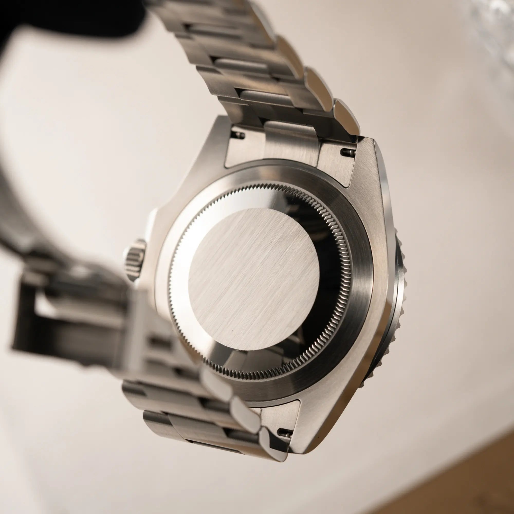 Produktfotografie der Produktfotografie der Rolex Submariner Date in schwarz mit Keramik-Lünette am Oyster-Stahlband aus 2023 mit dem 41mm-Oyster-Gehäuse zeigt den verschraubten Gehäuseboden