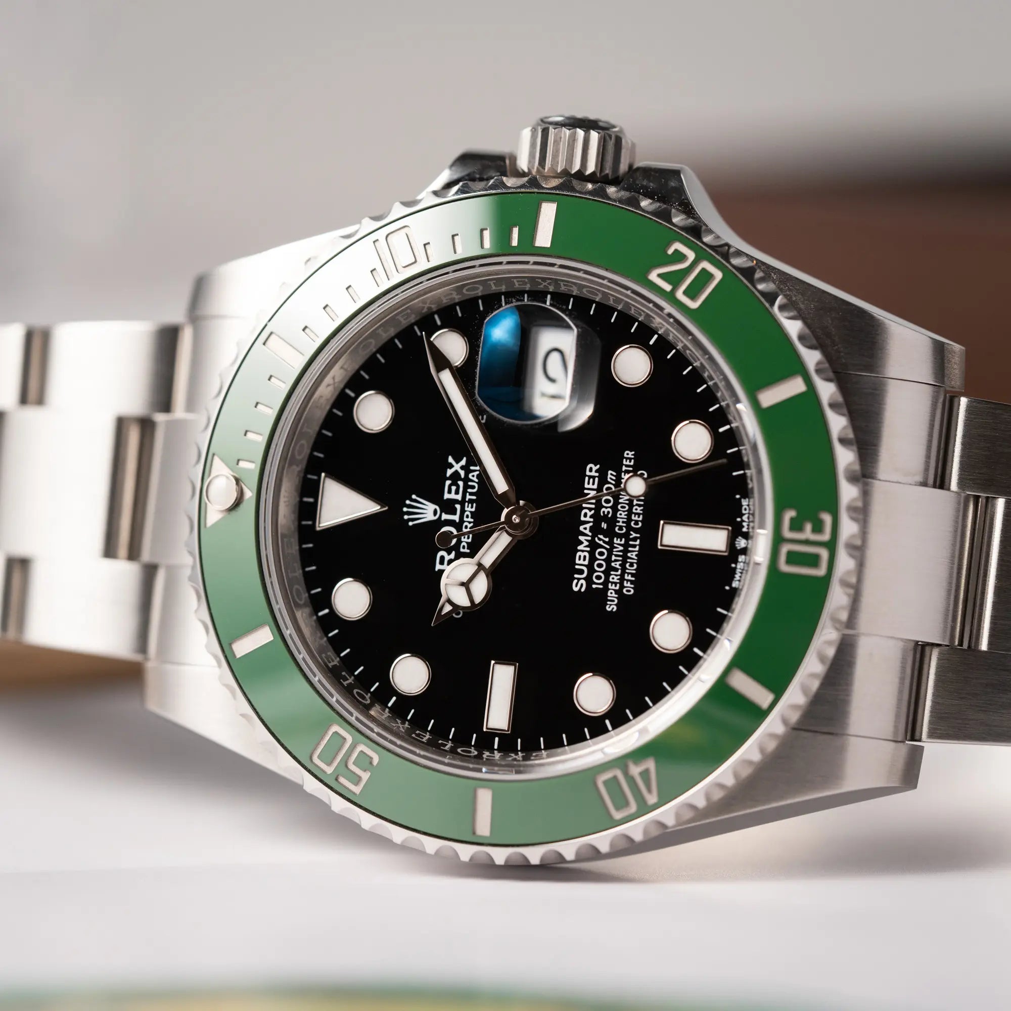 Detailaufnahme der seitlich auf dem Gehäuse liegenden Rolex Submariner Date 126610LV, Nickname "Starbucks", mit schwarzem Zifferblatt und grüner Keramik-Lünette in der MK2-Ausführung am Oyster-Stahl-Band