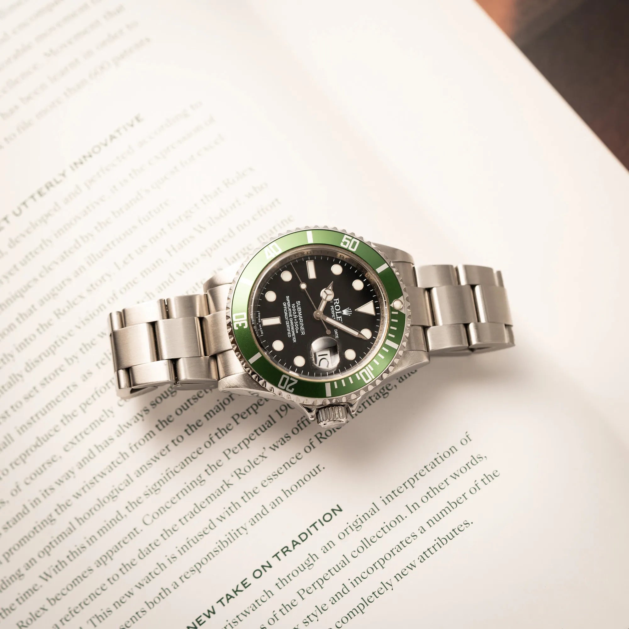 Rolex Submariner Date 16610LV mit der grünen Aluminium-Lünetten-Einlage liegt auf einem Buch