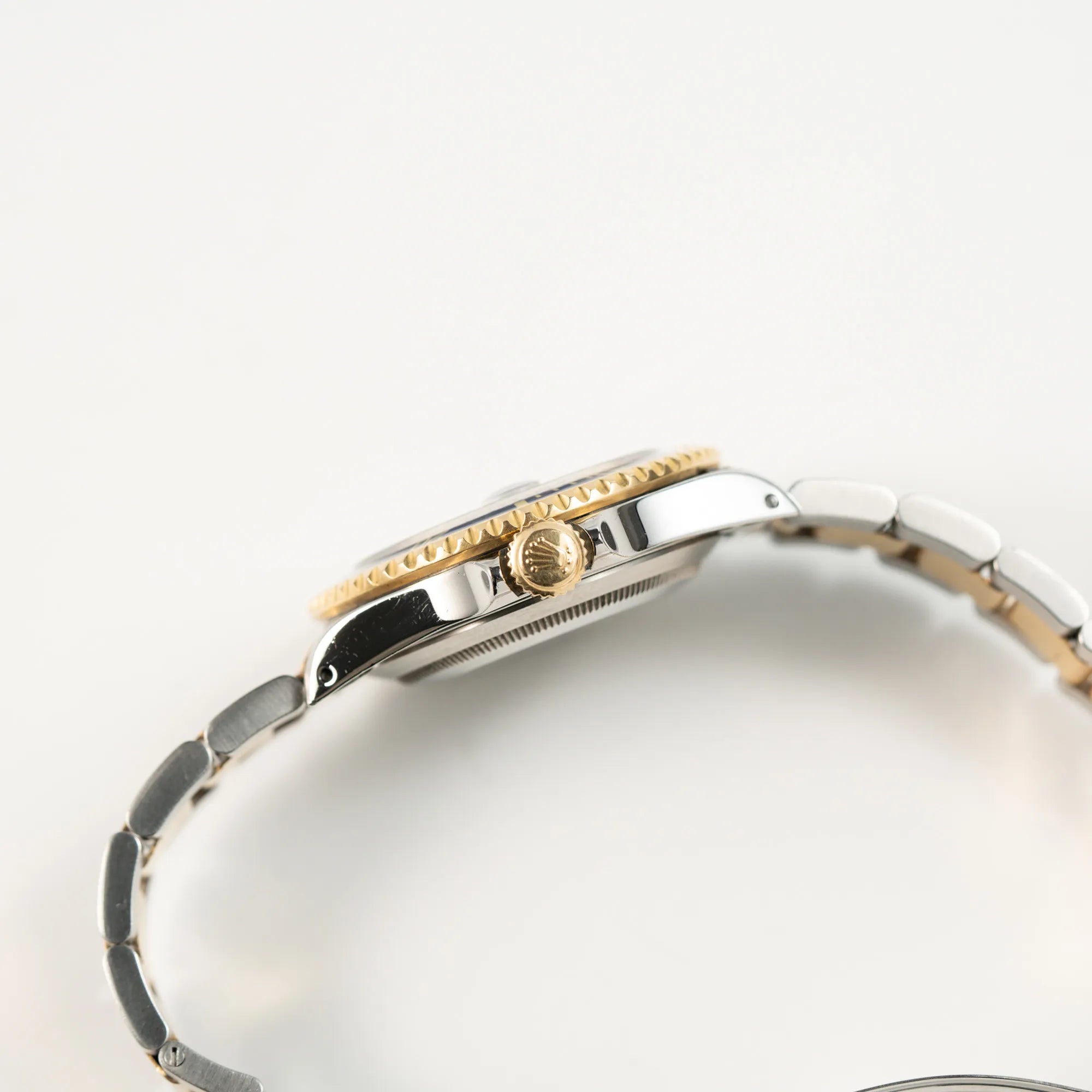 Seitliche Gehäuseflanke der der bicolor Rolex Submariner Date der Referenz 16613 mit dem Spitznamen "Bluesy" in Stahl-Gold mit blauem Zifferblatt mit Blick auf die gelbgoldene Aufzugskrone