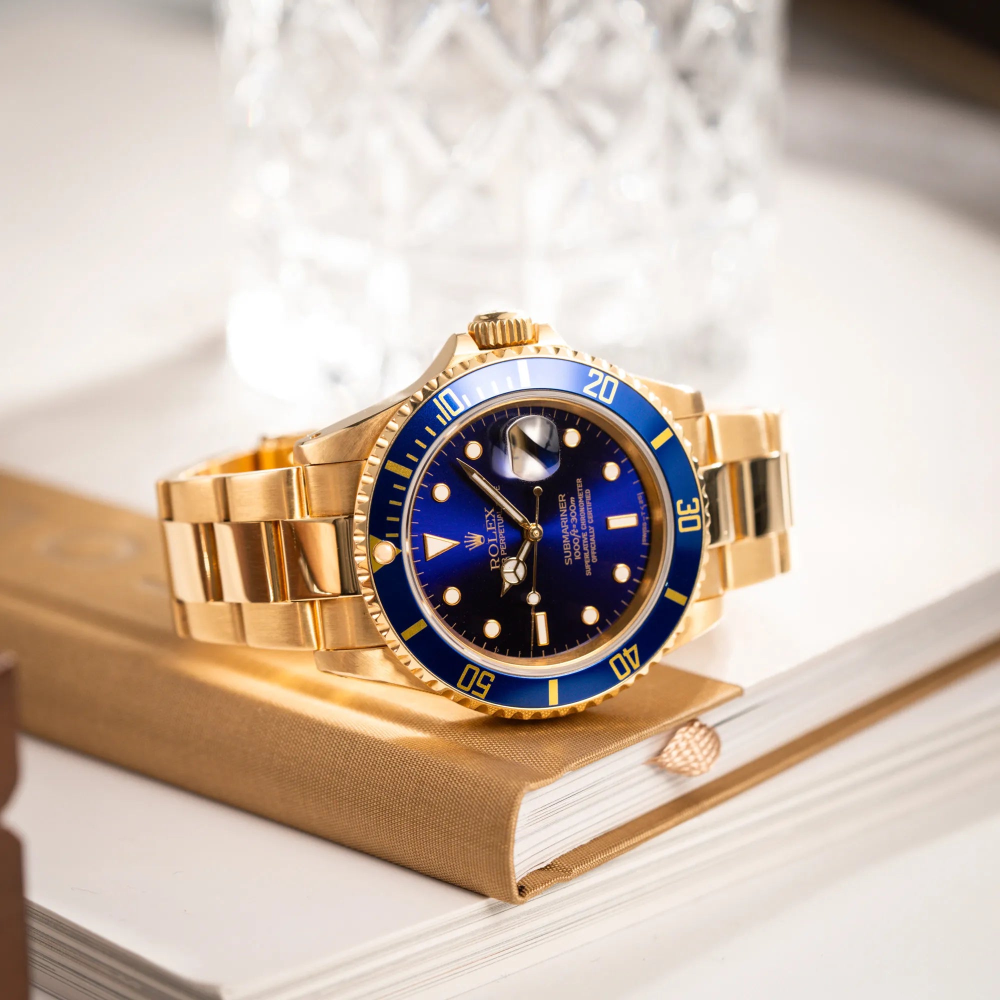 Produktfotografie der Rolex Submariner Date 16618 aus 18Karat Gelbgold mit blauer Lünetten-Einlage und einem sich von BLAU zu LILA verfärbtem Purple-Zifferblatt