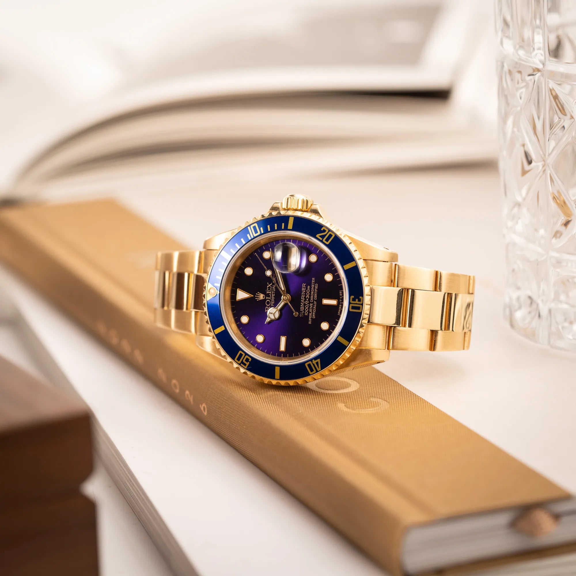 Produktfotografie der Rolex Submariner Date 16618 aus 18Karat Gelbgold mit blauer Lünetten-Einlage und einem sich von BLAU zu LILA verfärbtem Purple-Zifferblatt