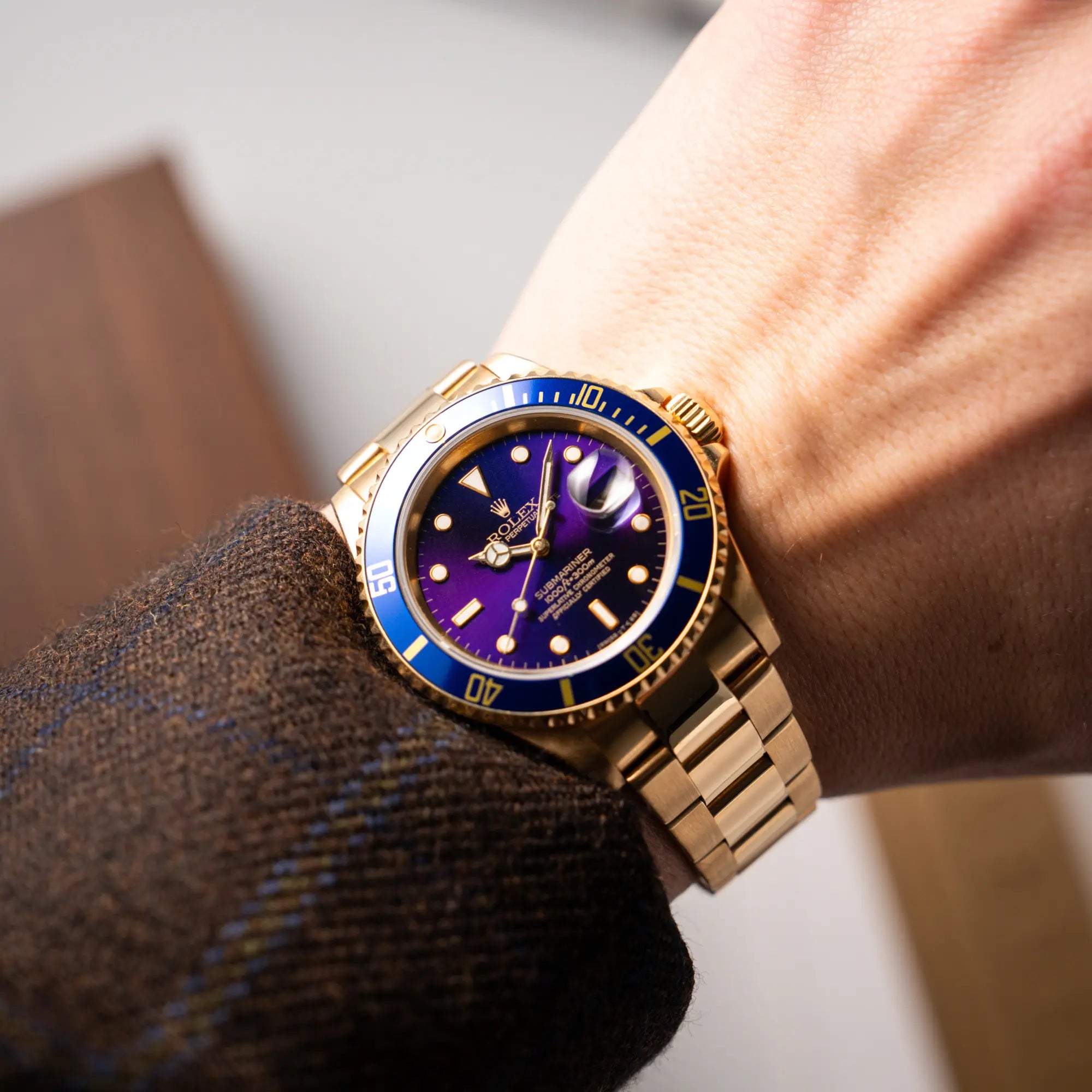 Mann trägt die Rolex Submariner Date 16618 aus 18Karat Gelbgold mit blauer Lünetten-Einlage und einem sich von BLAU zu LILA verfärbtem Purple-Zifferblatt an seinem Zifferblatt