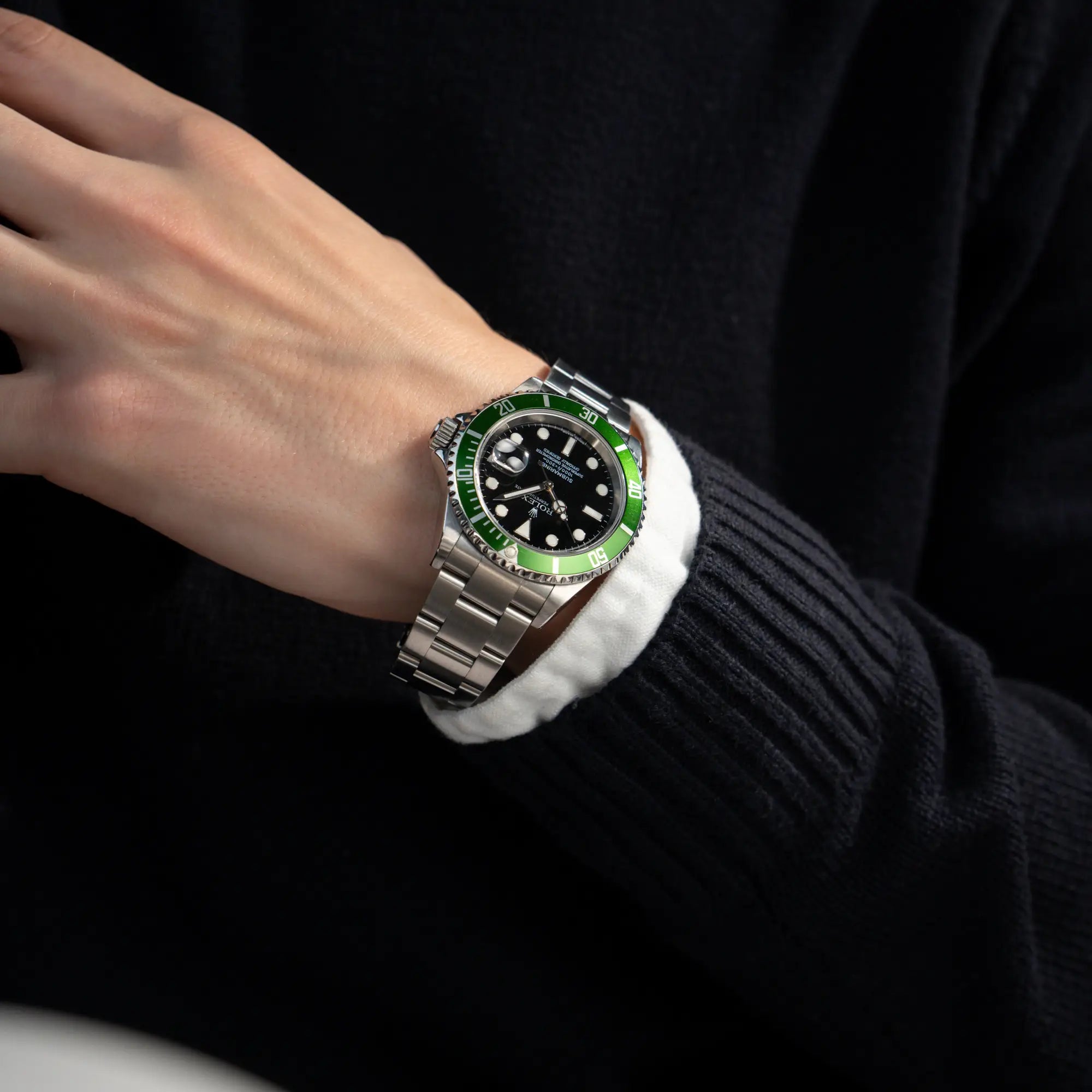 Mann trägt die Rolex Submariner Date 16610LV "Kermit" mit der schwarzem Zifferblatt und der grünen Aluminium-Lünette an seinem Handgelenk