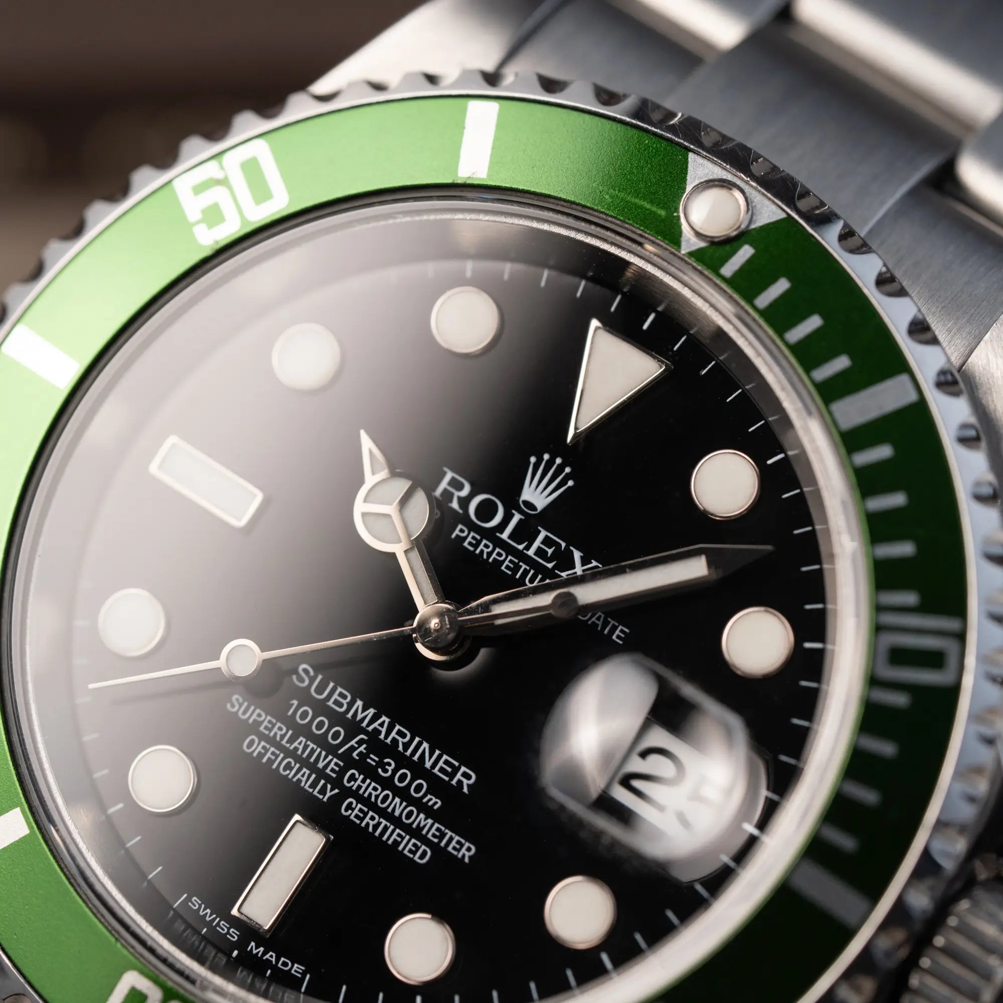Makroaufnahme der Rolex Submariner Date 16610LV "Kermit" mit der schwarzem Zifferblatt und der grünen Aluminium-Lünette mit Fokus auf dem Zeigersatz