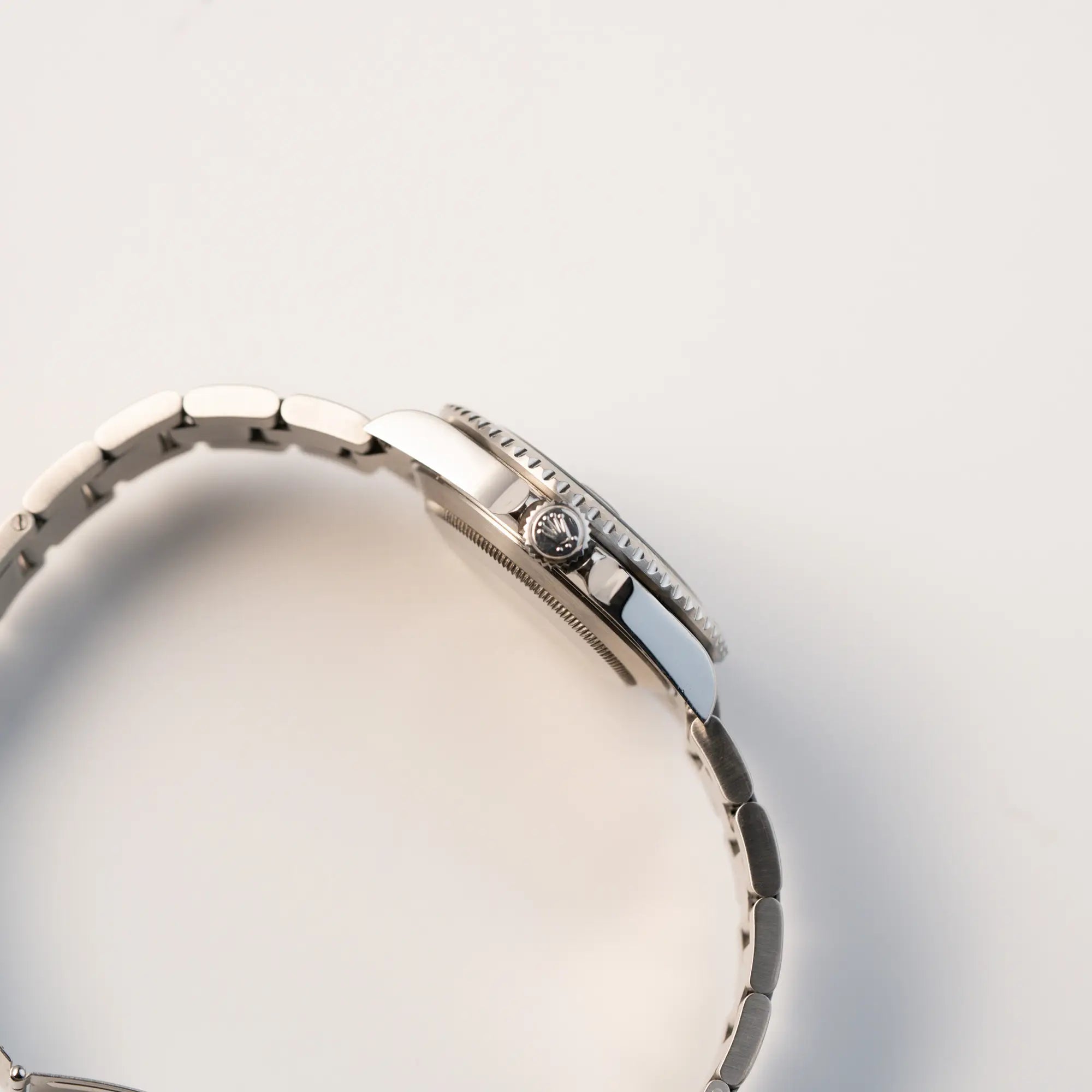 Seitliches Gehäuse der Rolex Submariner Date 16610LV "Kermit" mit der schwarzem Zifferblatt und der grünen Aluminium-Lünette mit Blick auf die Aufzugskrone