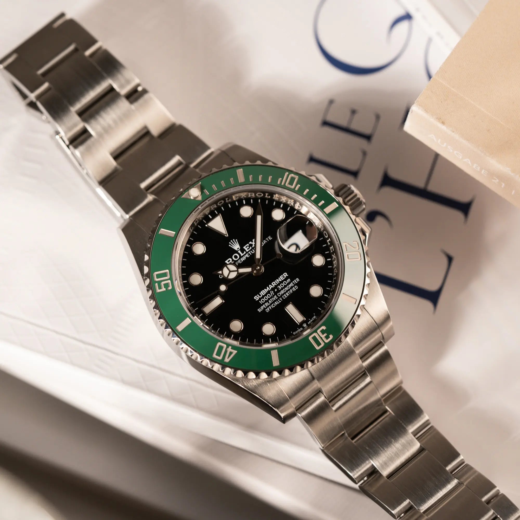 Produktfoto der auf dem Uhrenband liegenden Rolex Submariner Date Starbucks 126610LV mit schwarzem Zifferblatt und grüner Cerachrom-Lünette
