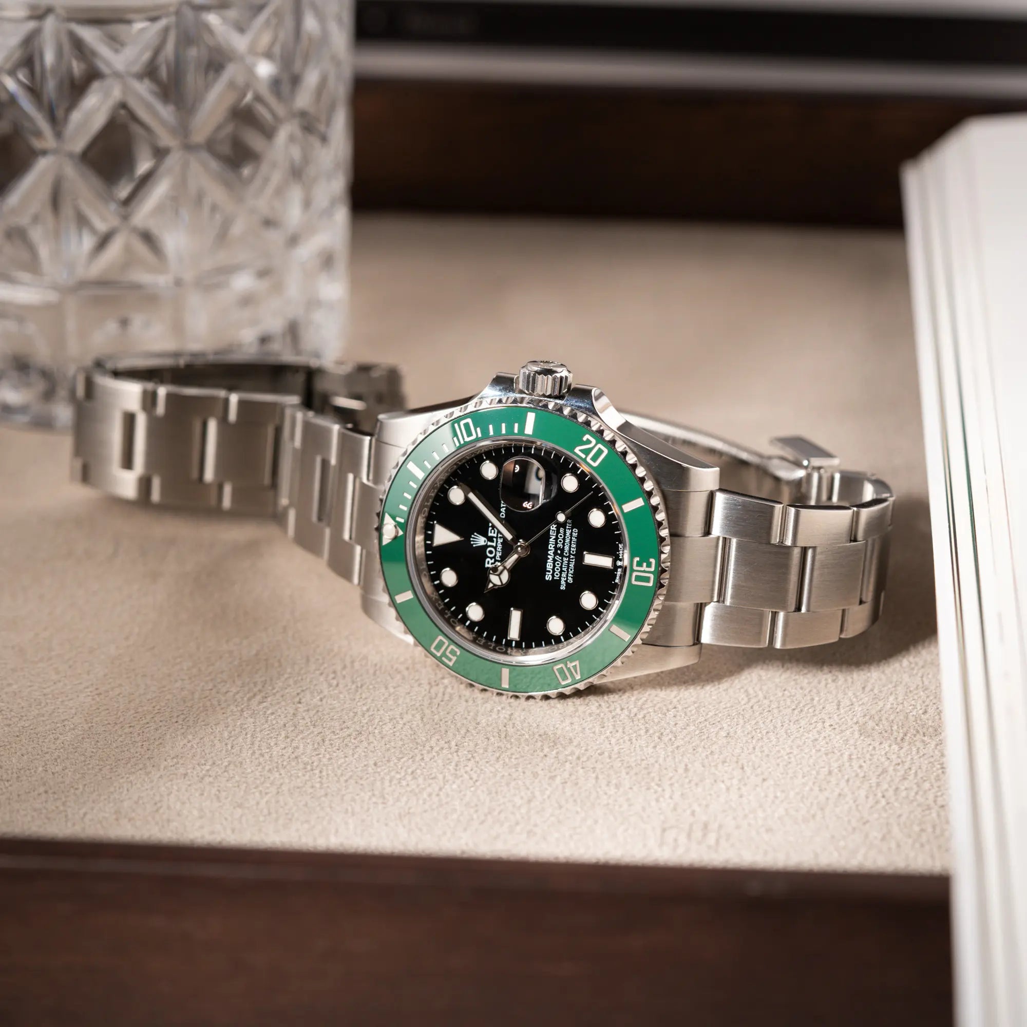 Rolex Submariner Date Starbucks 126610LV mit schwarzem Zifferblatt und grüner Cerachrom-Lünette liegt auf einem Juwelierstablet