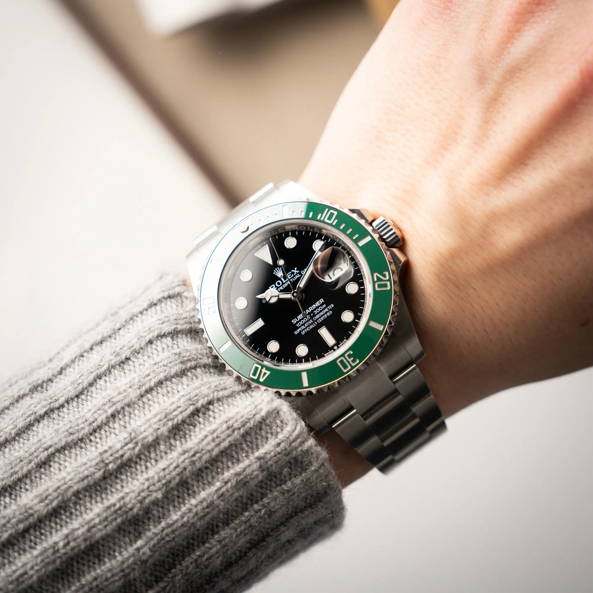 Mann trägt die Rolex Submariner Date "Starbucks" der Referenz 126610LV mit der modelltypischen grünen Keramik-Lünette, die im Kontrast zu dem schwarzen Zifferblatt steht an seinem Handgelenk