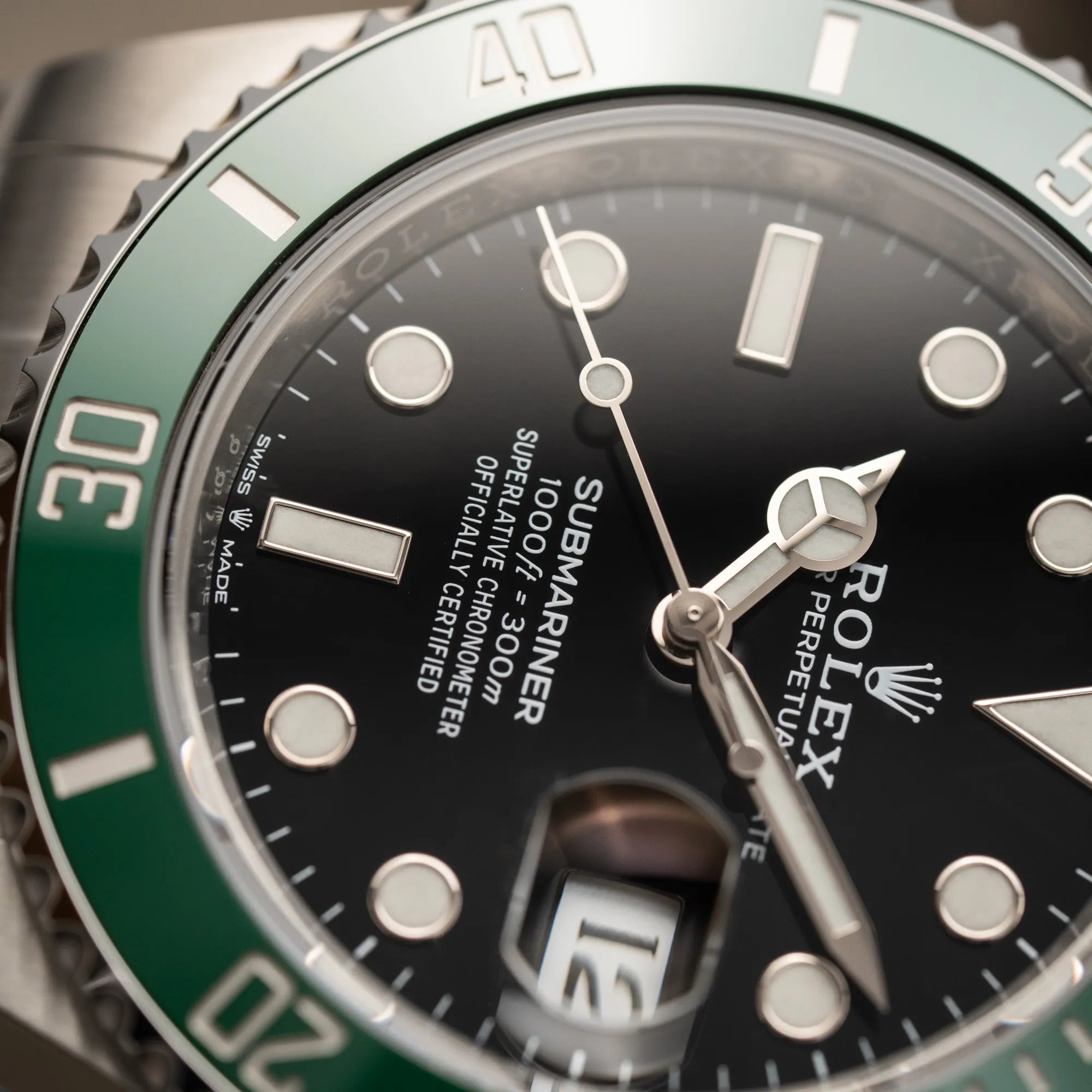 Detailaufnahme der Rolex Submariner Date "Starbucks" der Referenz 126610LV mit der modelltypischen grünen Keramik-Lünette, die im Kontrast zu dem schwarzen Zifferblatt steht, mit Fokus auf dem Submariner Schriftzug bei 6 Uhr