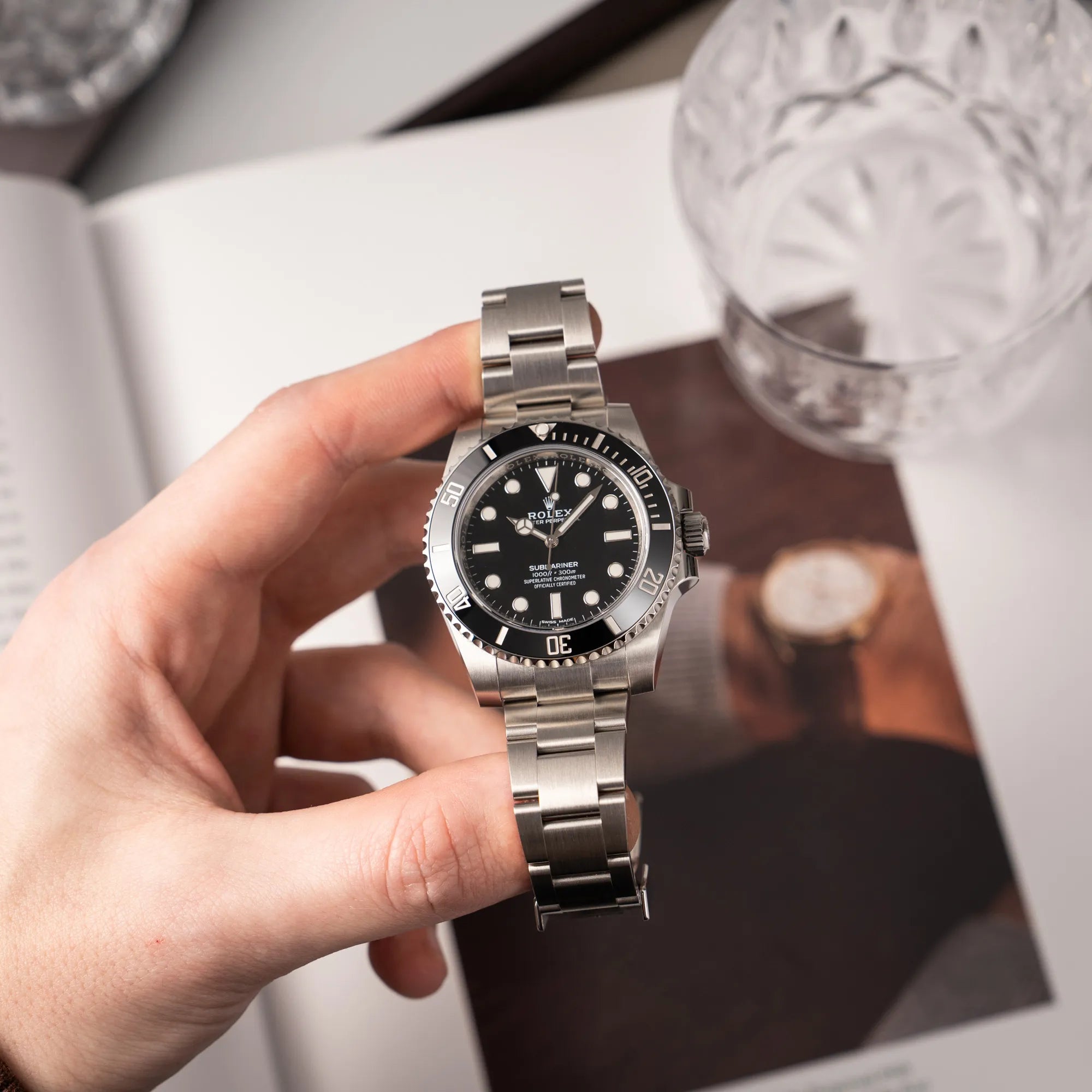 Mann präsentiert die Rolex Submariner 114060 No Date aus 2019 in der klassischen schwarzen Ausführung im Neuzustand in die Kamera